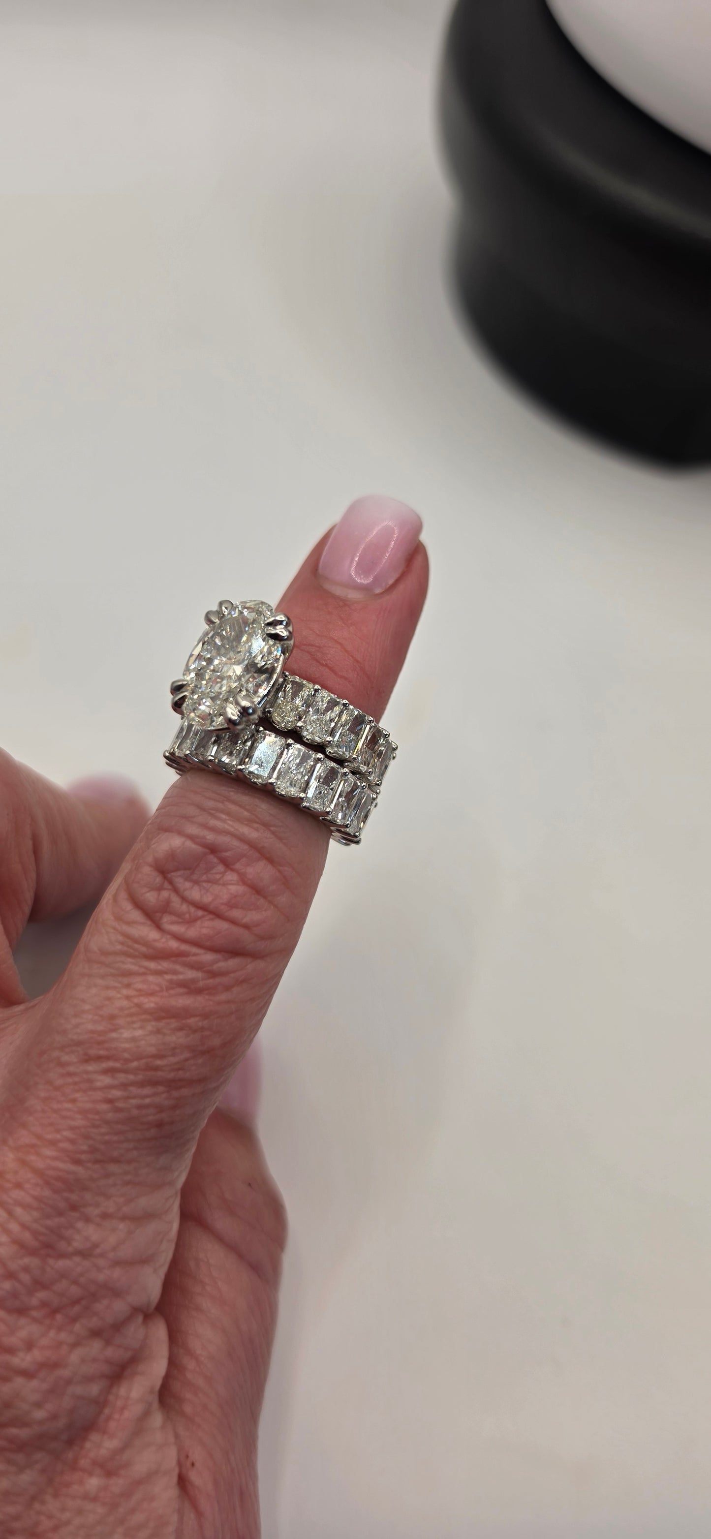 Close-up of a hand wearing two diamond rings on a neutral background