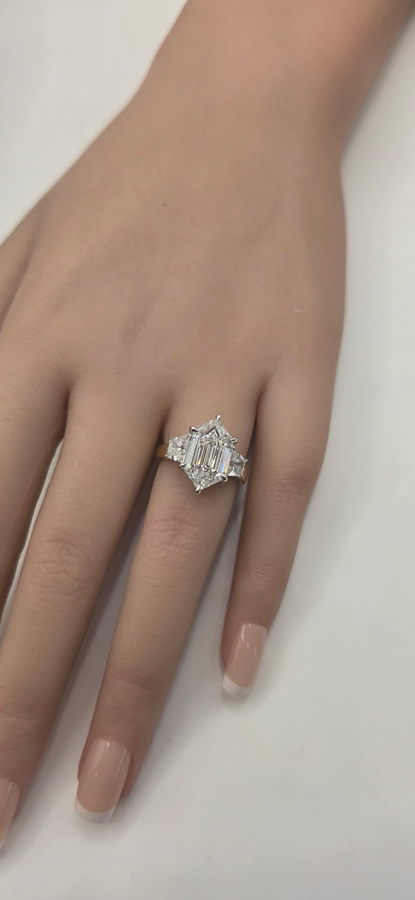 Hand wearing a diamond ring on a plain background