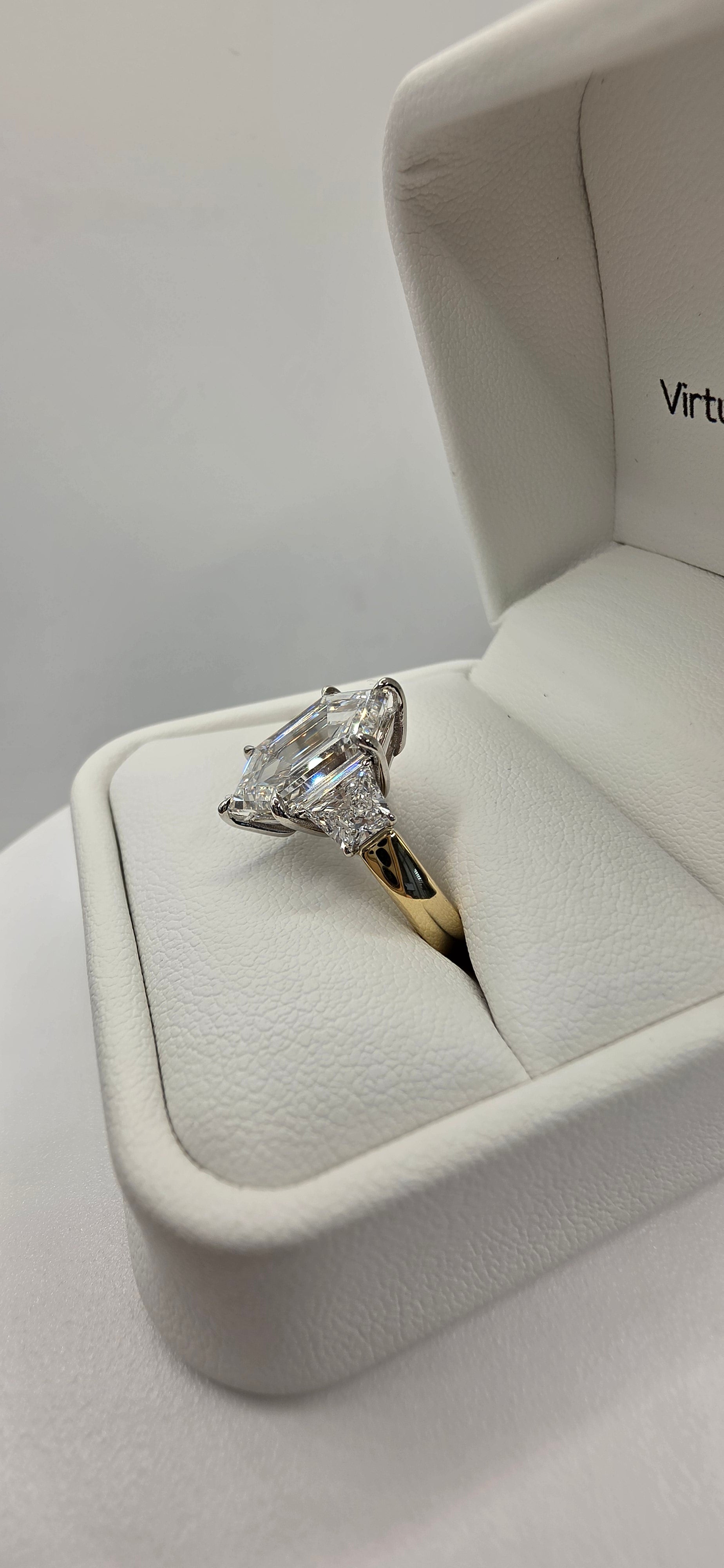 Diamond ring in a white jewelry box on a light gray background