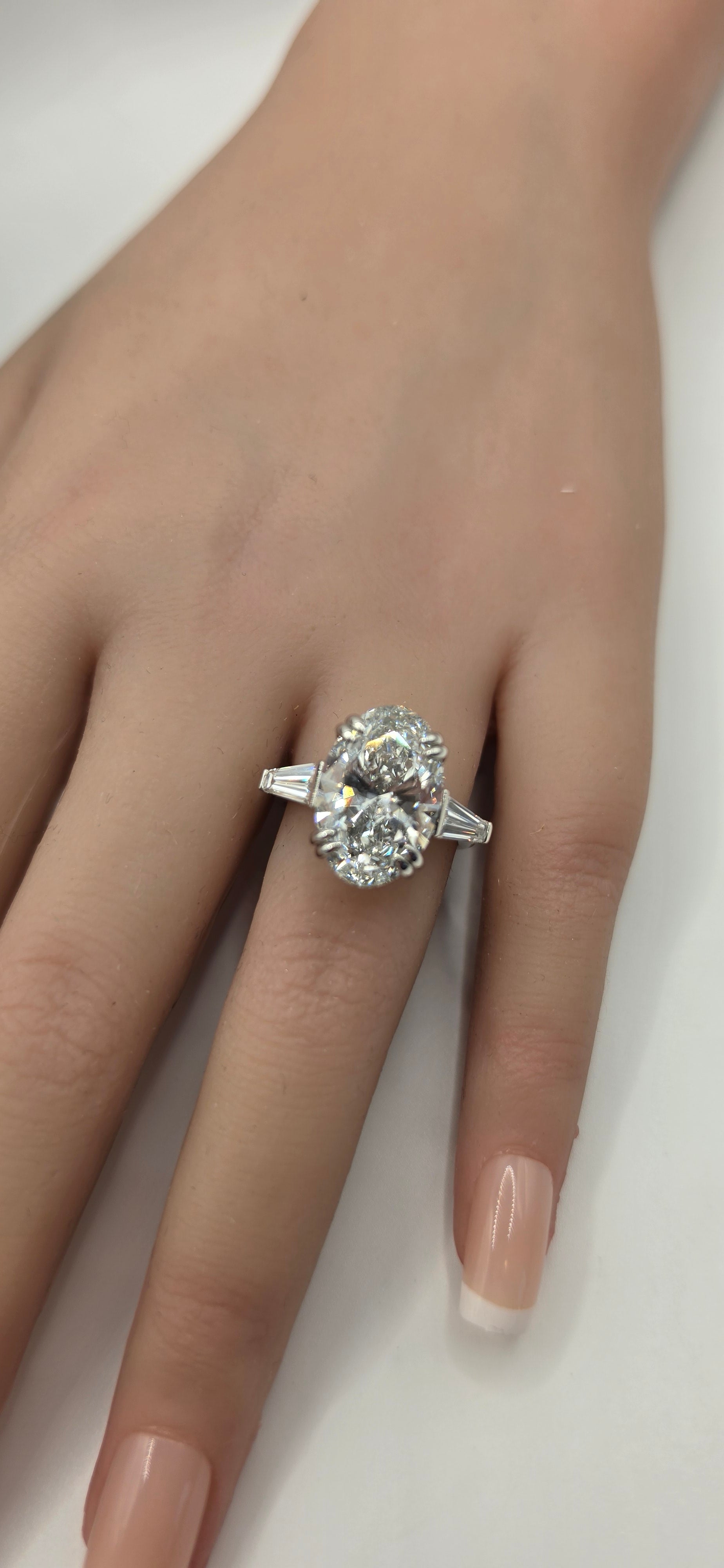 Silver ring with a large diamond on a hand against a white background