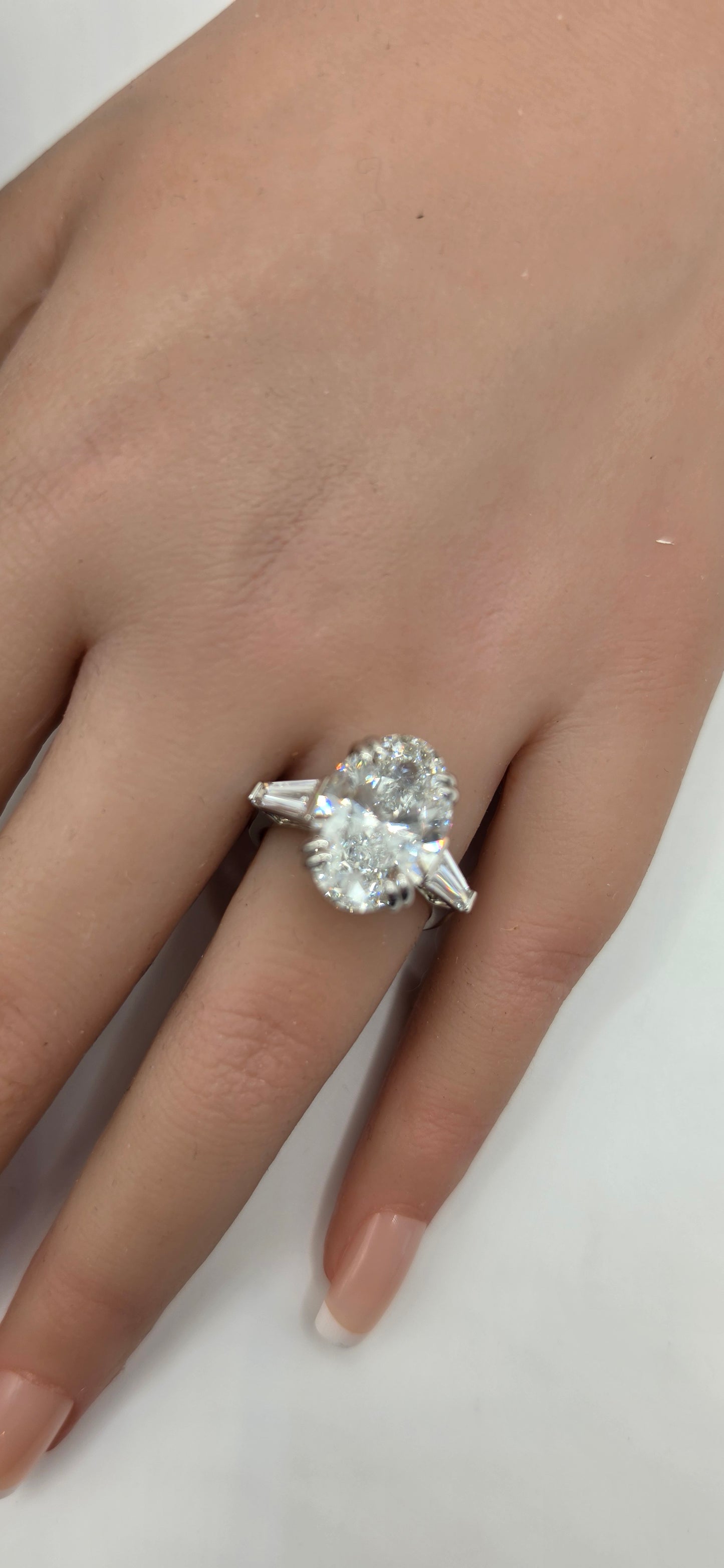 Diamond ring on a finger against a plain background