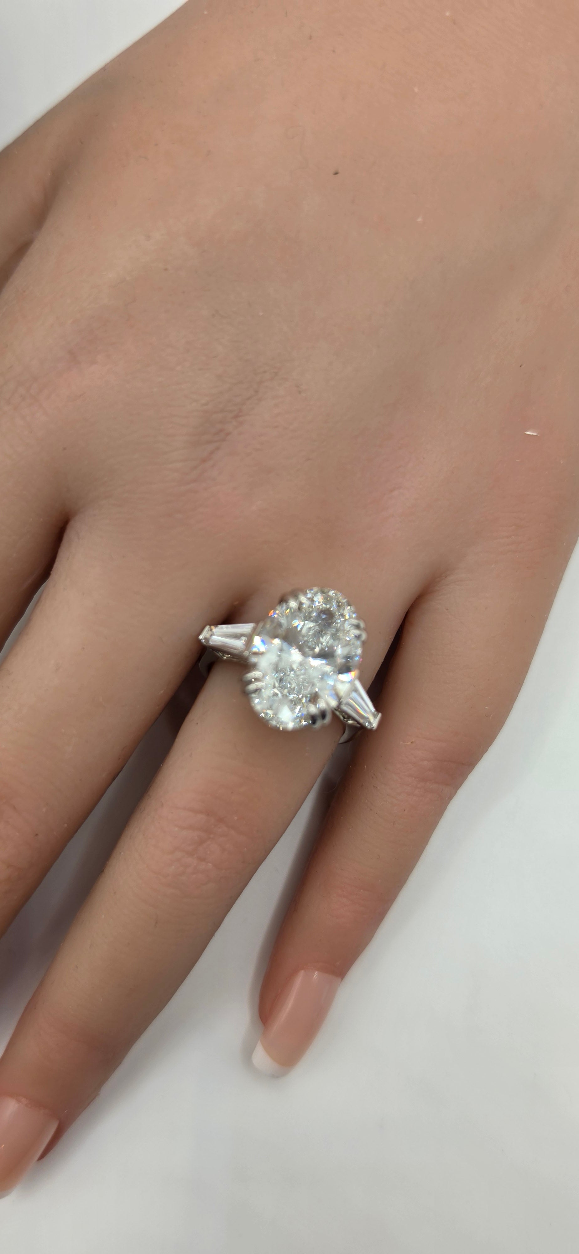 Diamond ring on a finger against a plain background
