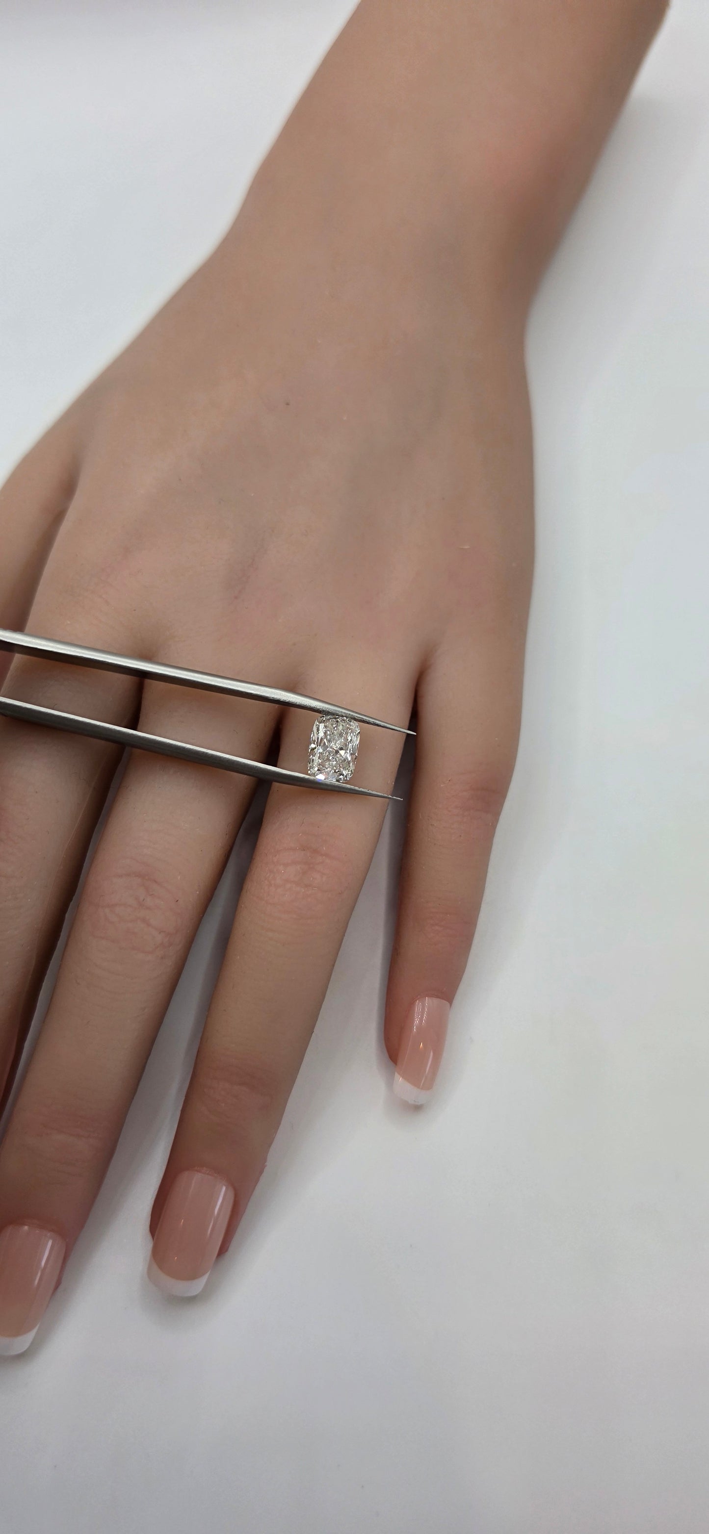 Hand wearing a diamond ring on a plain background