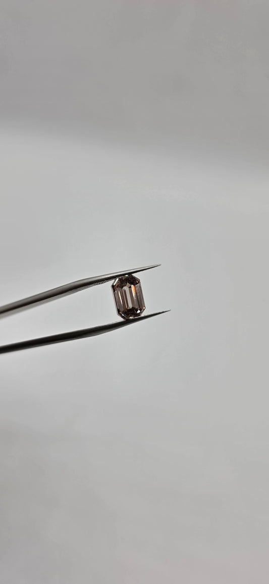 Diamond held between tweezers against a gray background
