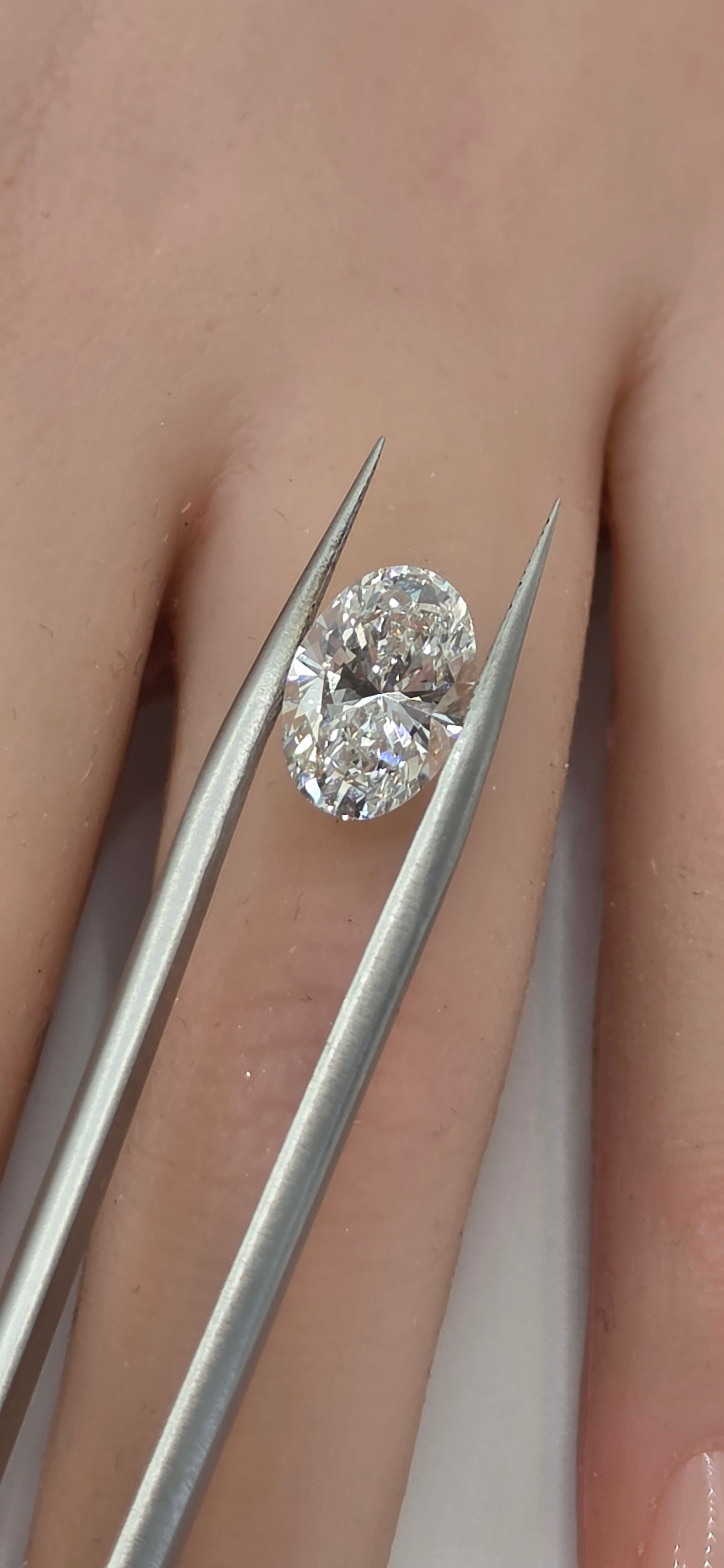 Diamond held between tweezers against a skin background