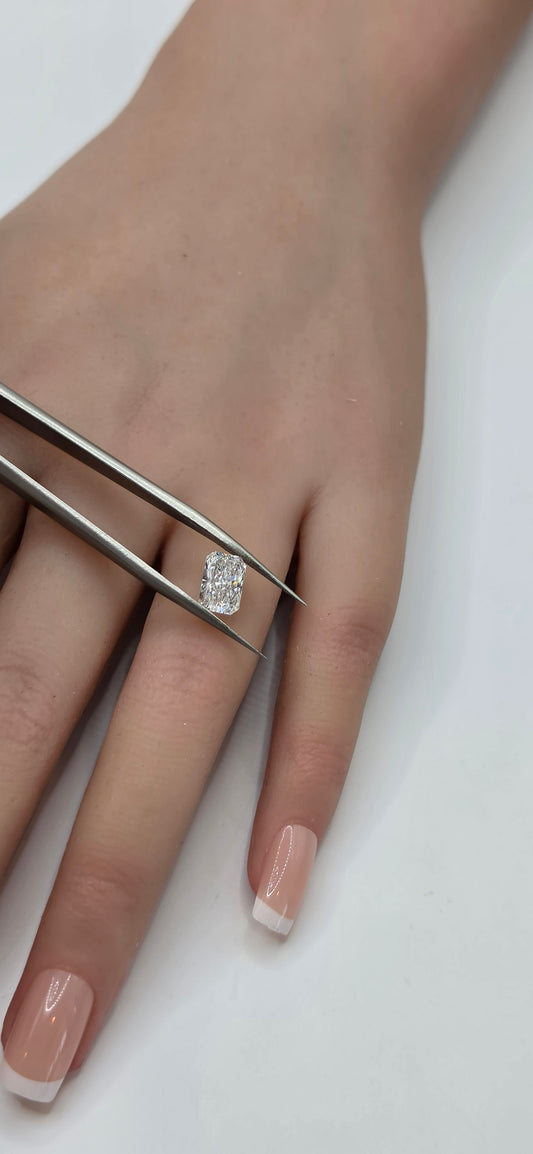 Diamond ring being held by tweezers on a hand with a white background