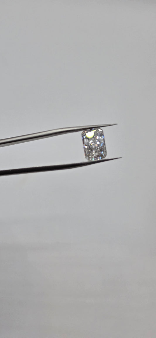 Diamond held between tweezers against a gray background