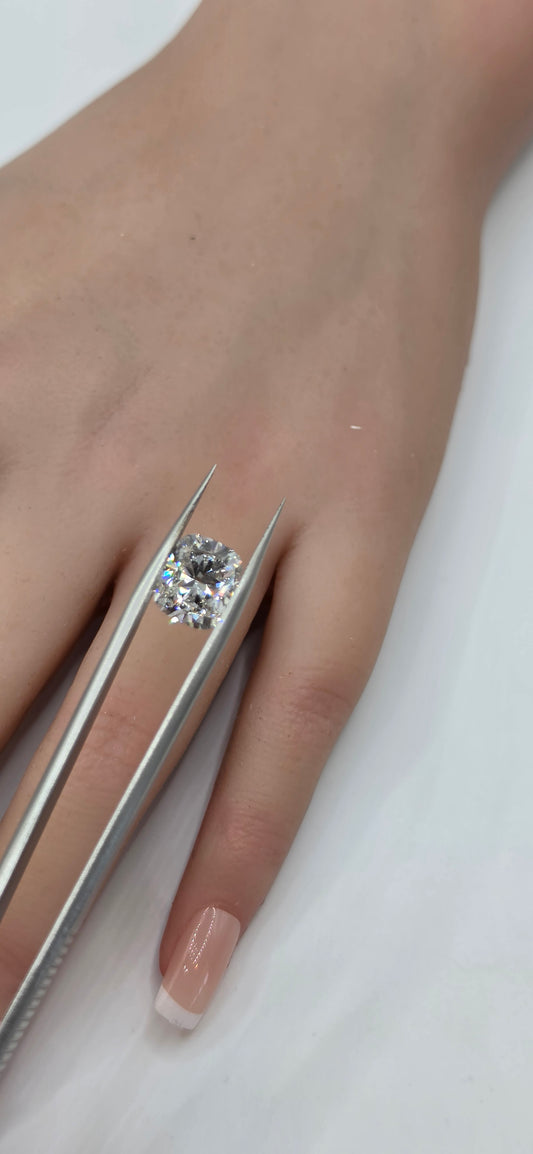 Diamond being held with tweezers against a hand on a white background