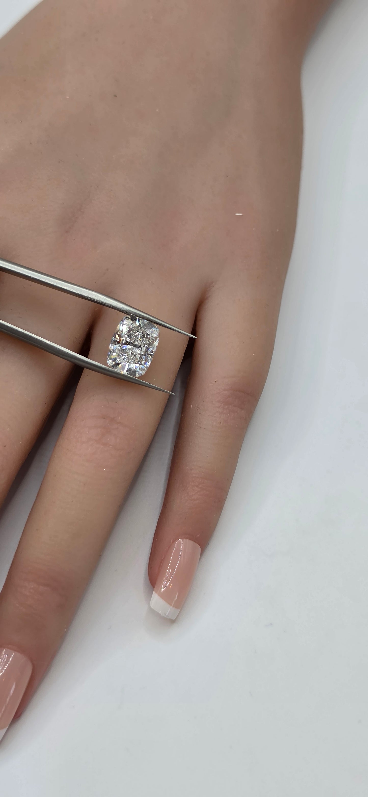 Hand wearing a silver ring with a diamond on a white background