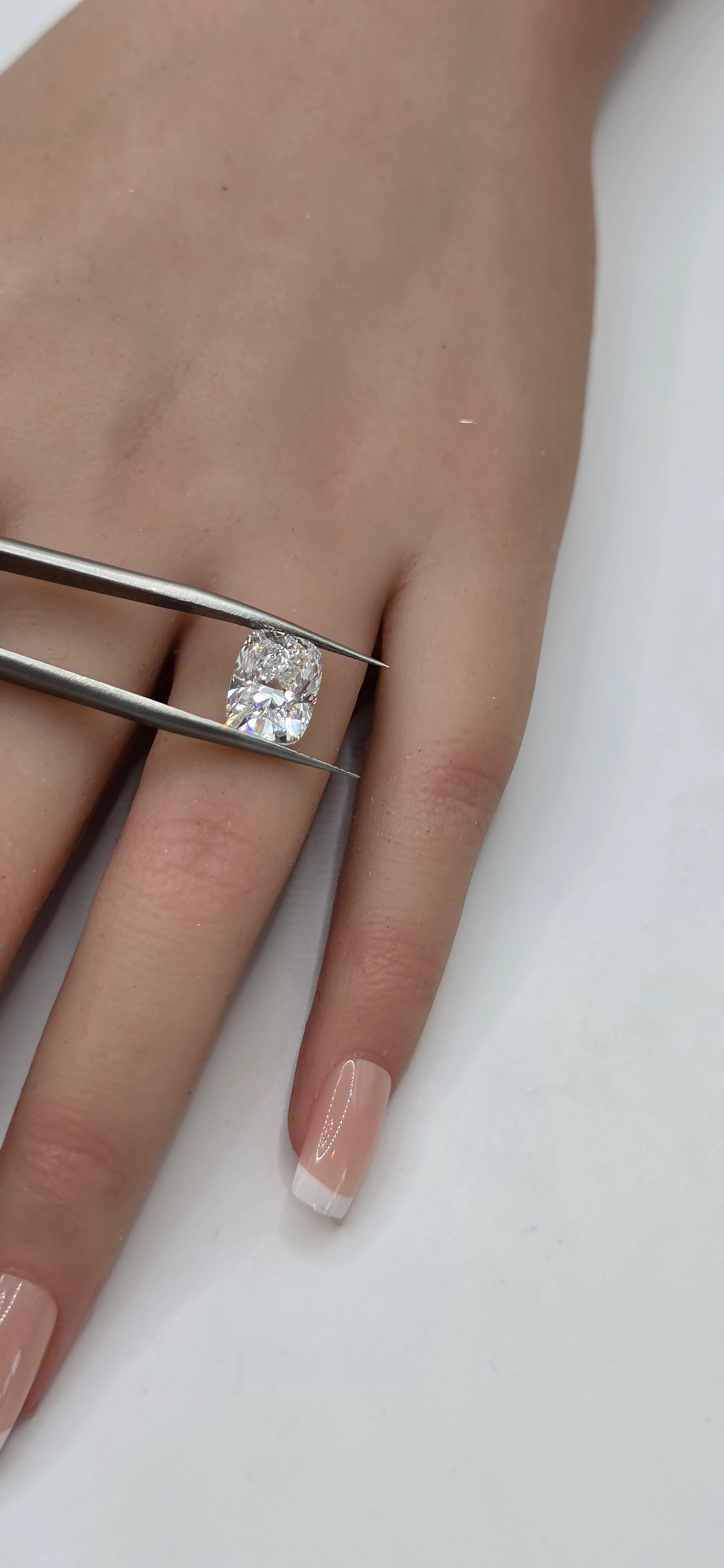 Hand wearing a silver ring with a diamond on a white background