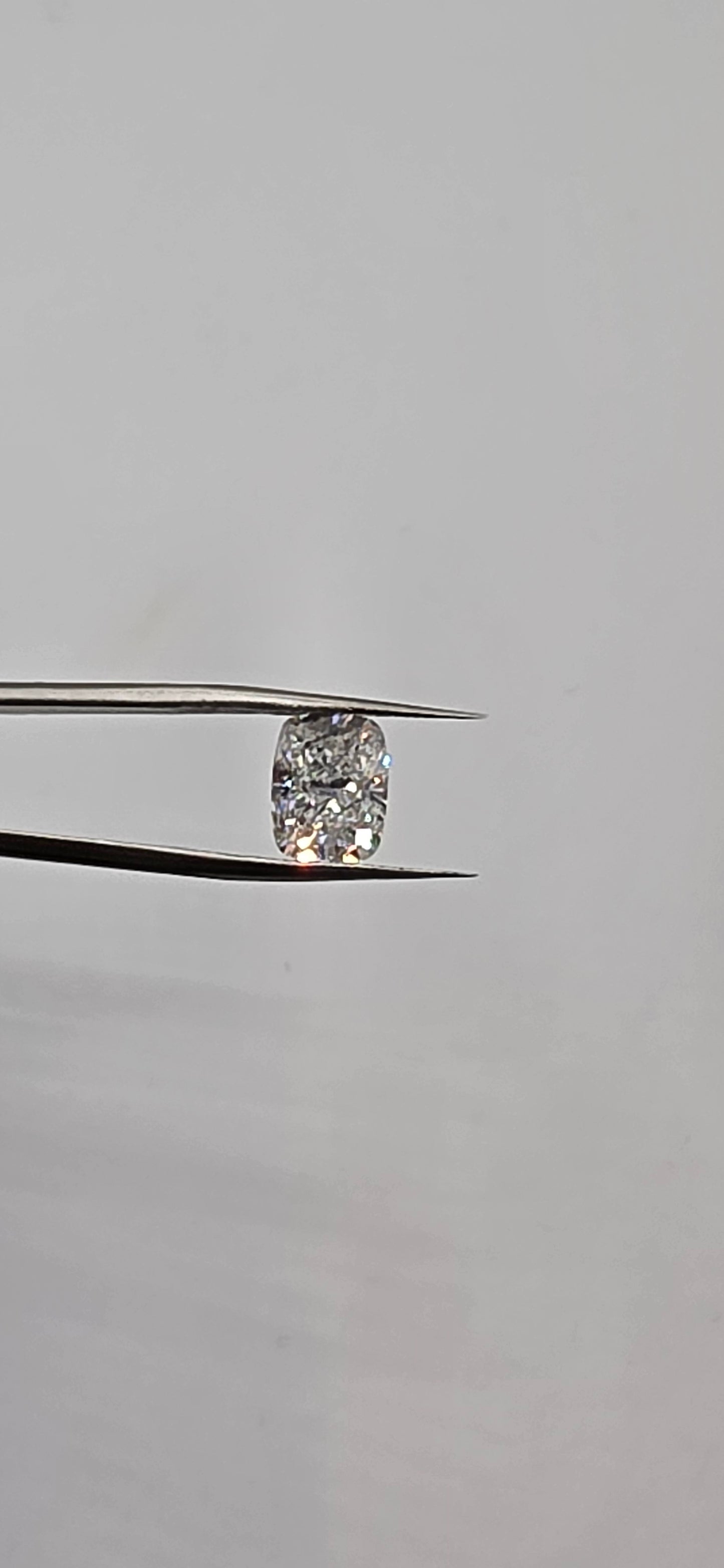 Diamond held between tweezers against a gray background