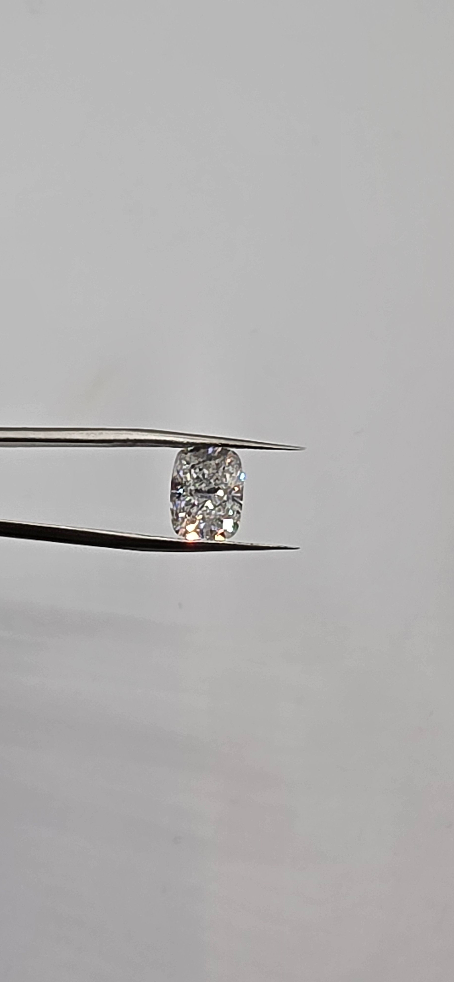 Diamond held between tweezers against a gray background