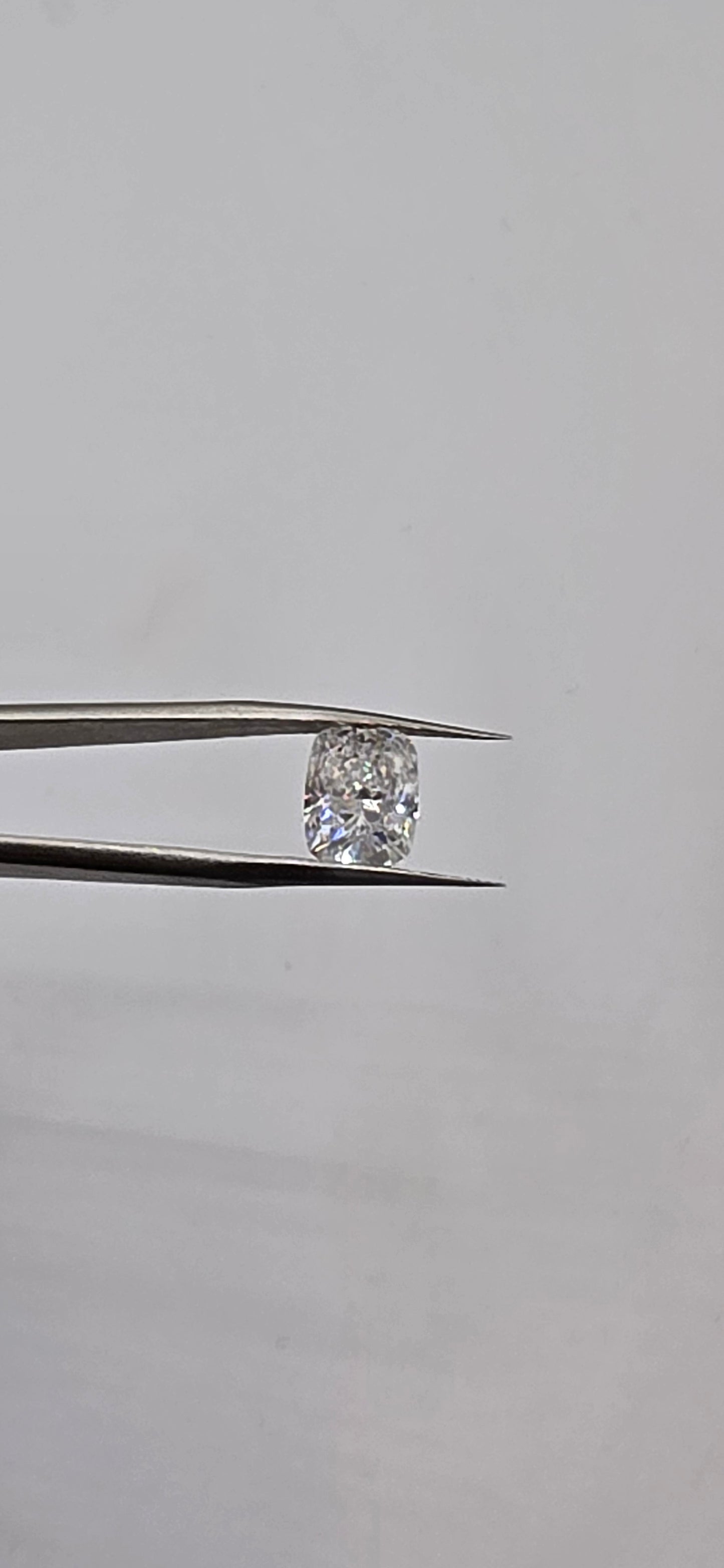 Diamond held between tweezers against a neutral background