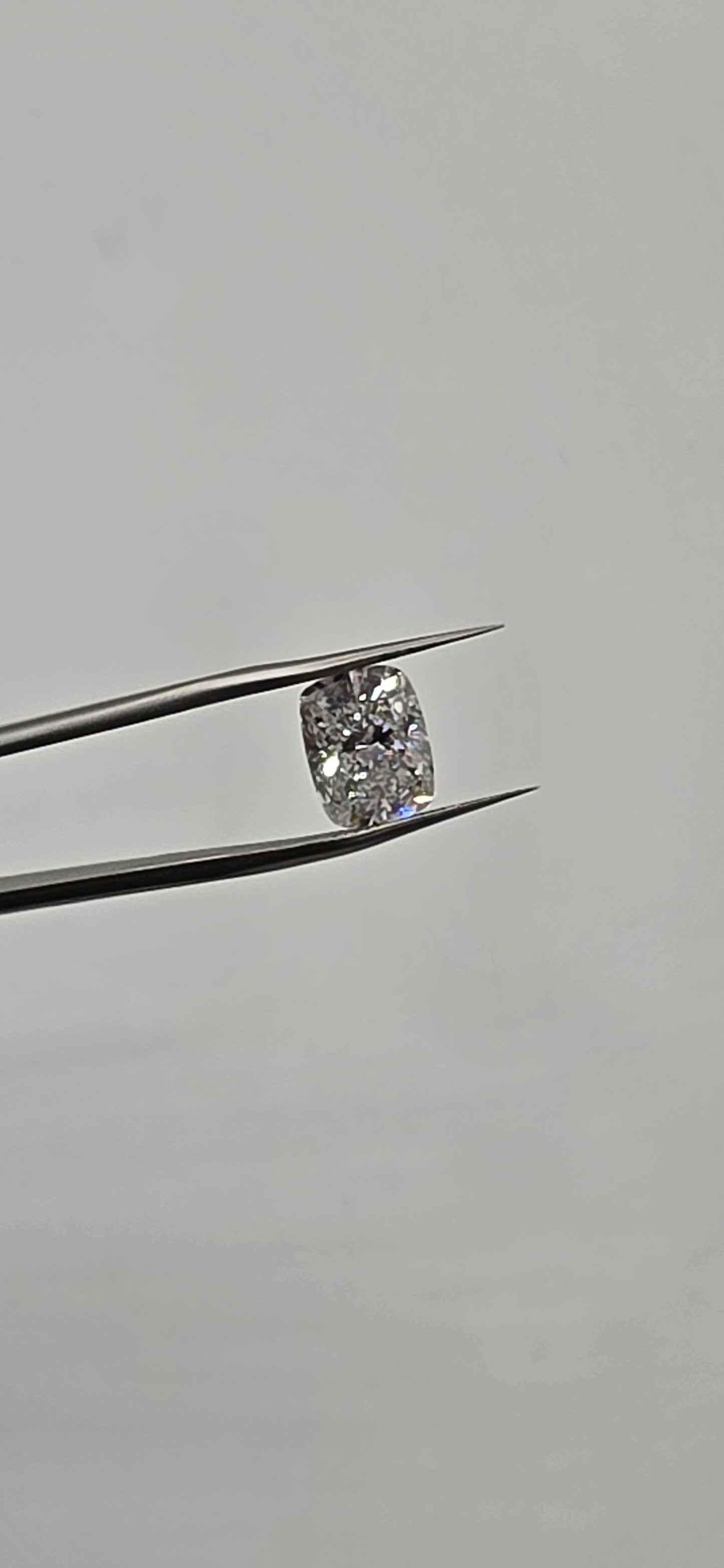 Diamond held between tweezers against a gray background