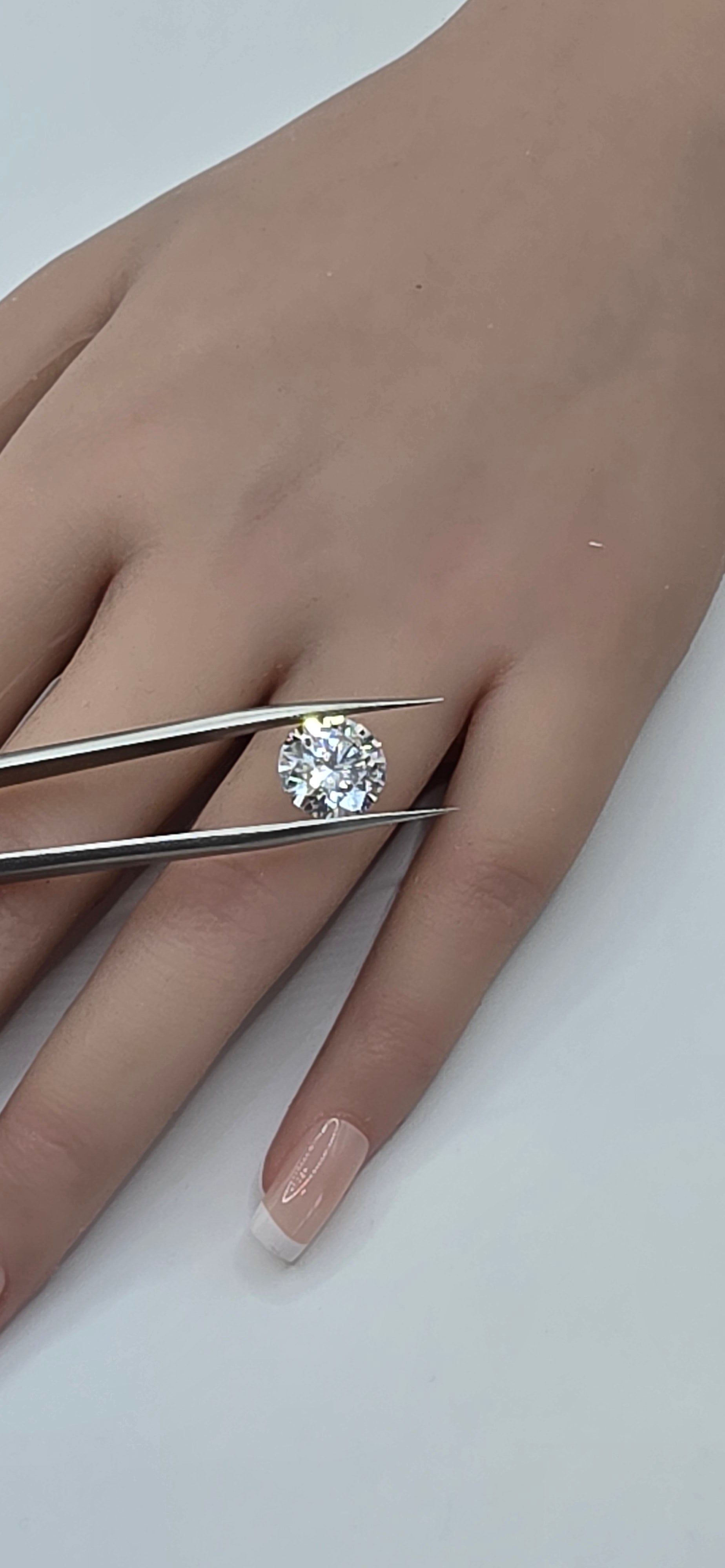 Diamond ring being held by tweezers on a hand with a white background