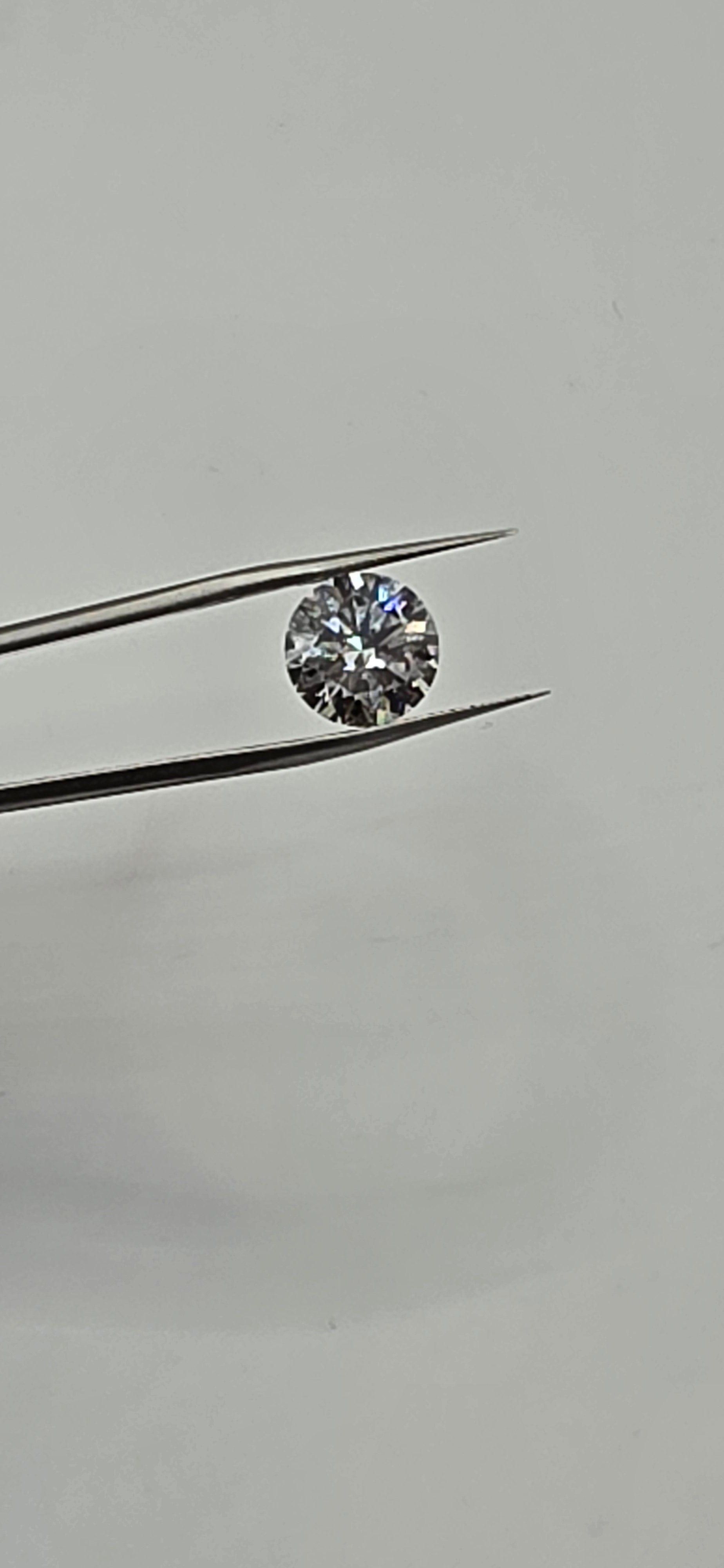 Diamond held between tweezers against a gray background