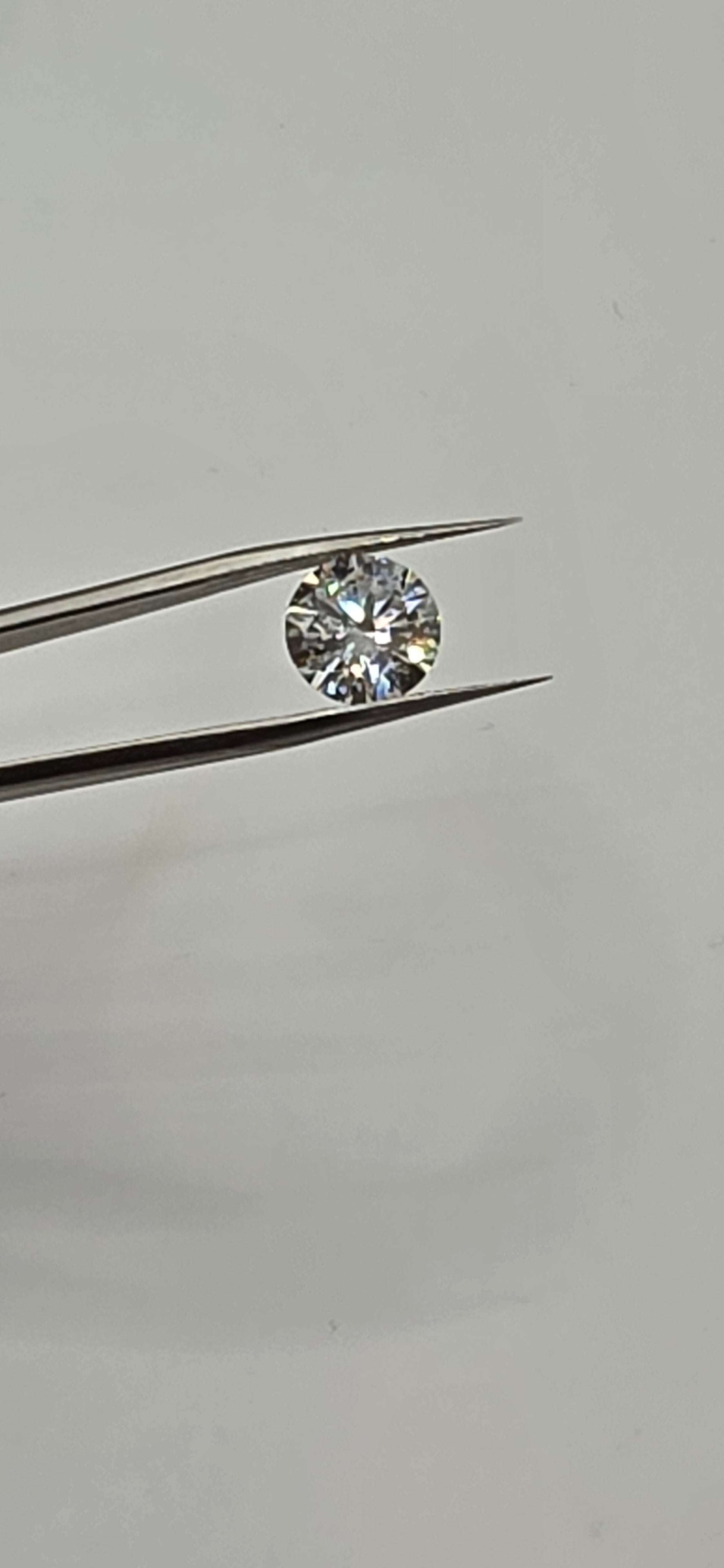 Diamond held between tweezers against a gray background