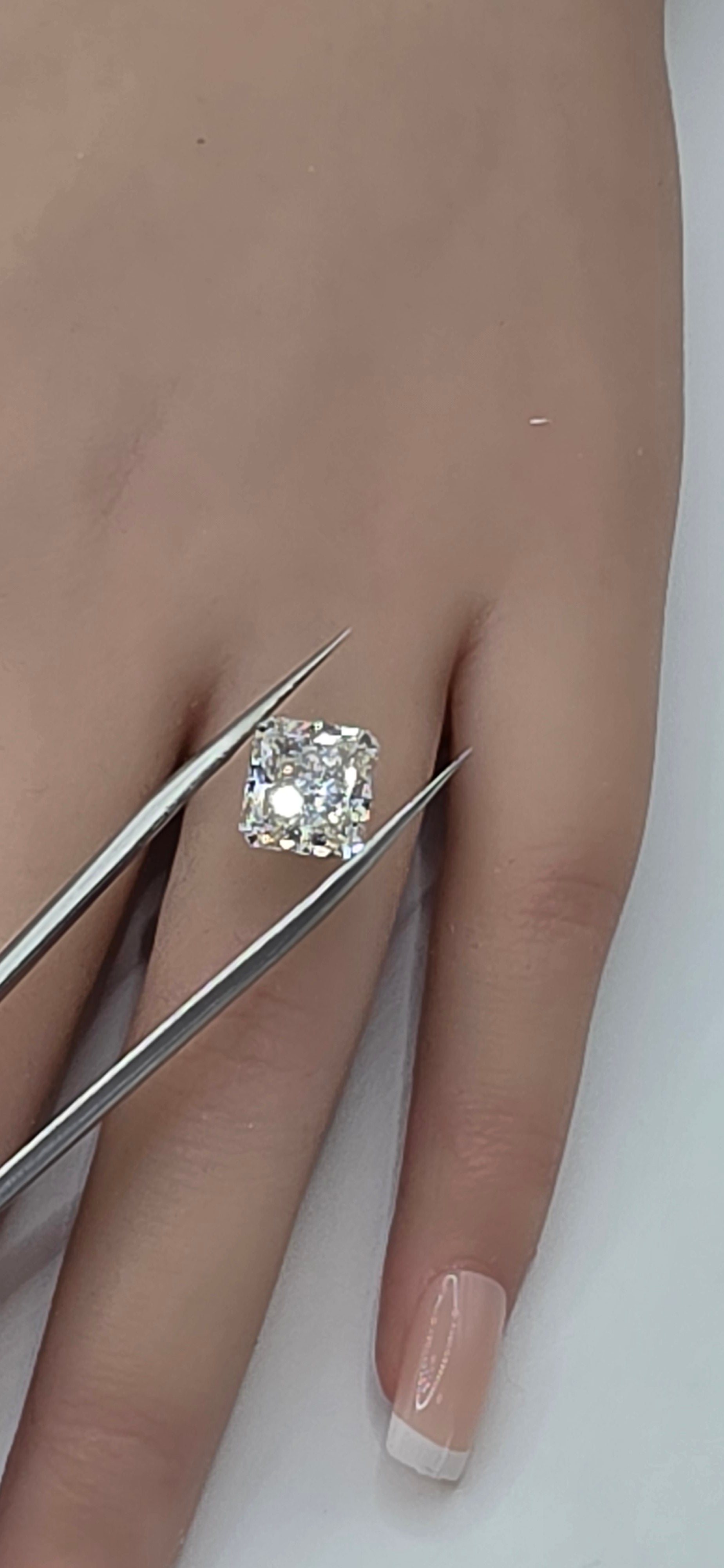 Diamond held by tweezers on a hand with a white background