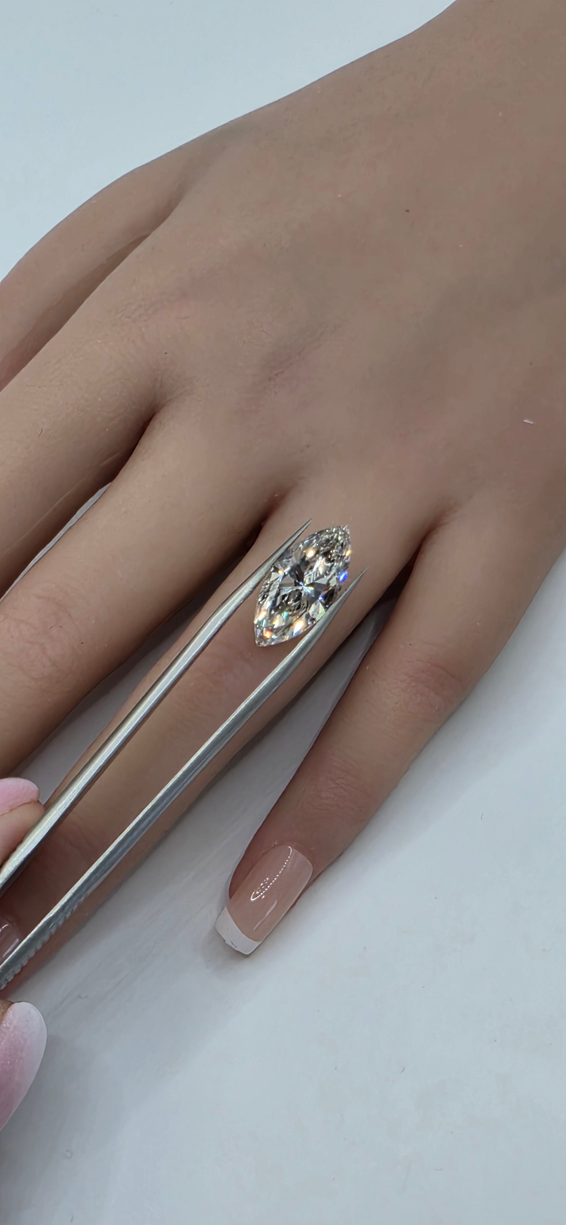 Hand wearing a ring with a large diamond on a white background