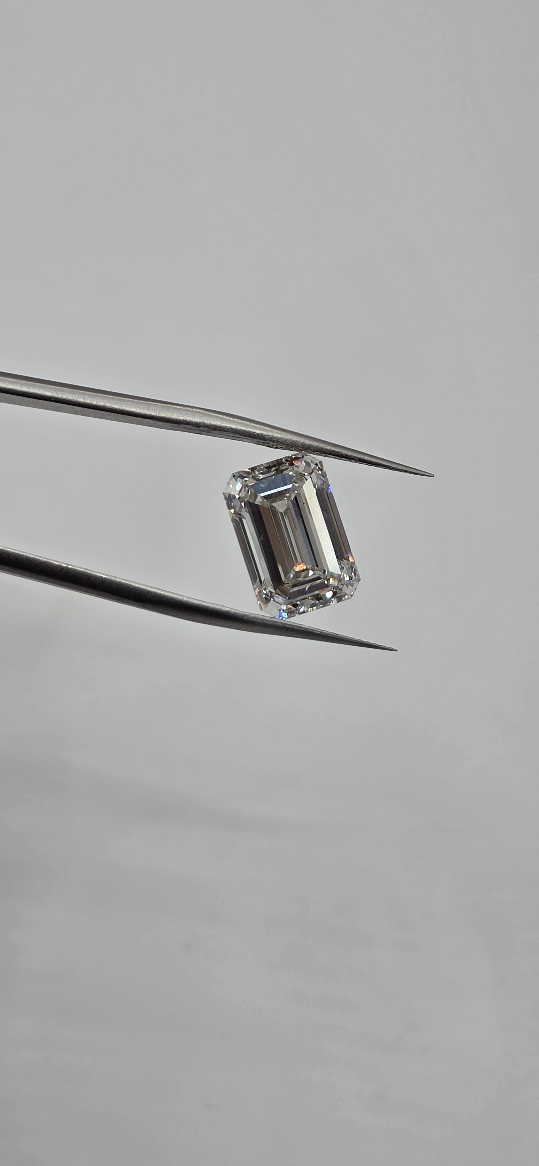 Diamond held between tweezers against a gray background