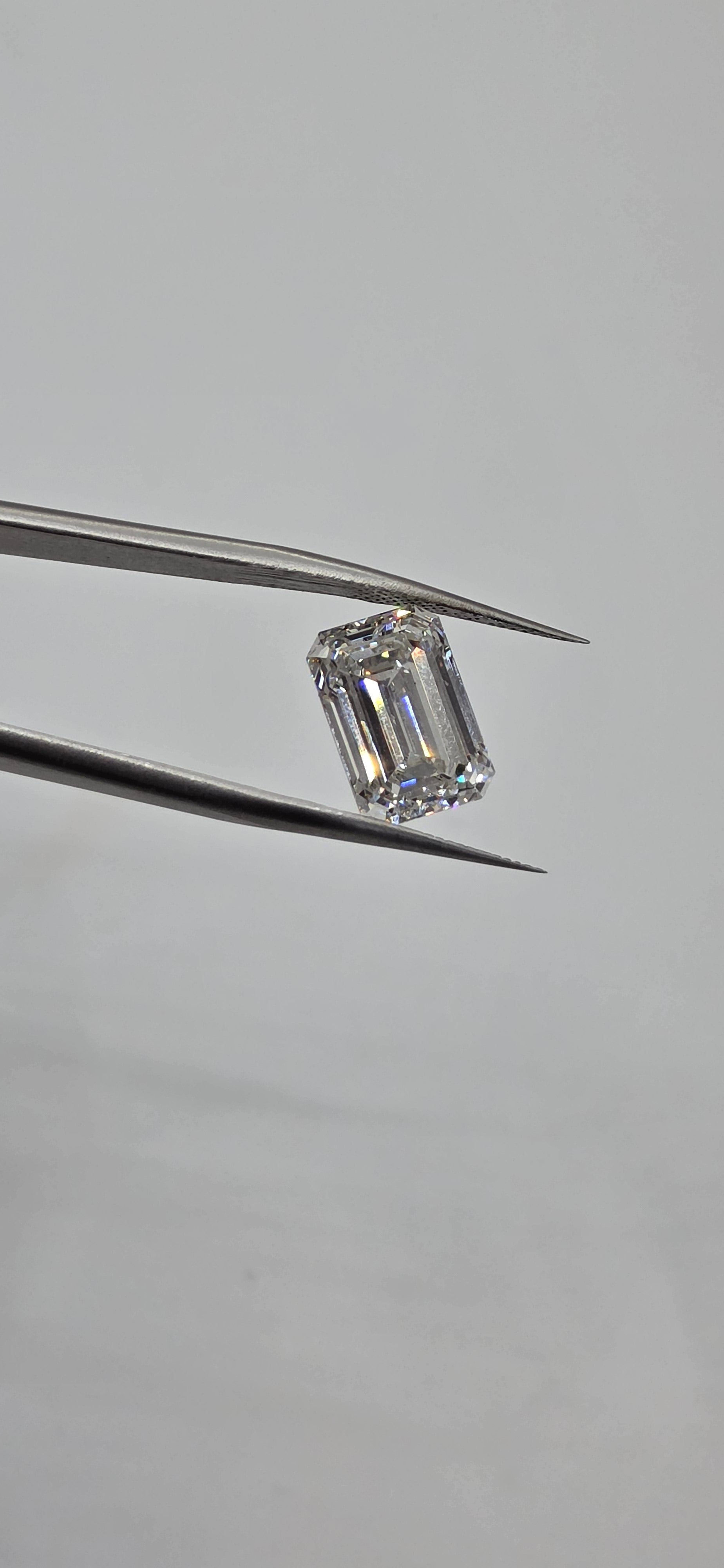 Diamond held between tweezers on a gray background