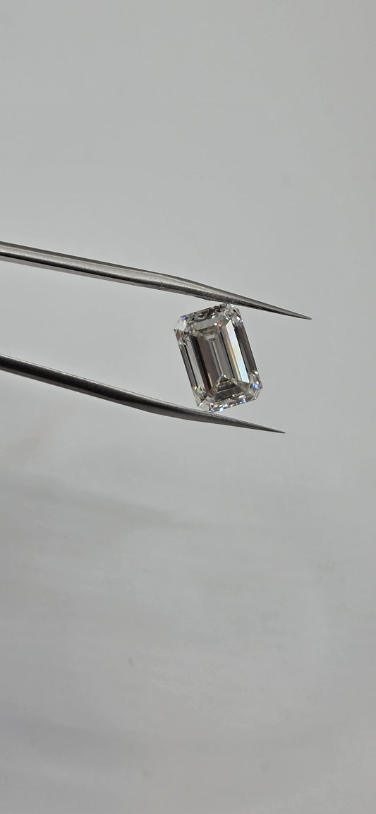 Diamond held between tweezers on a gray background