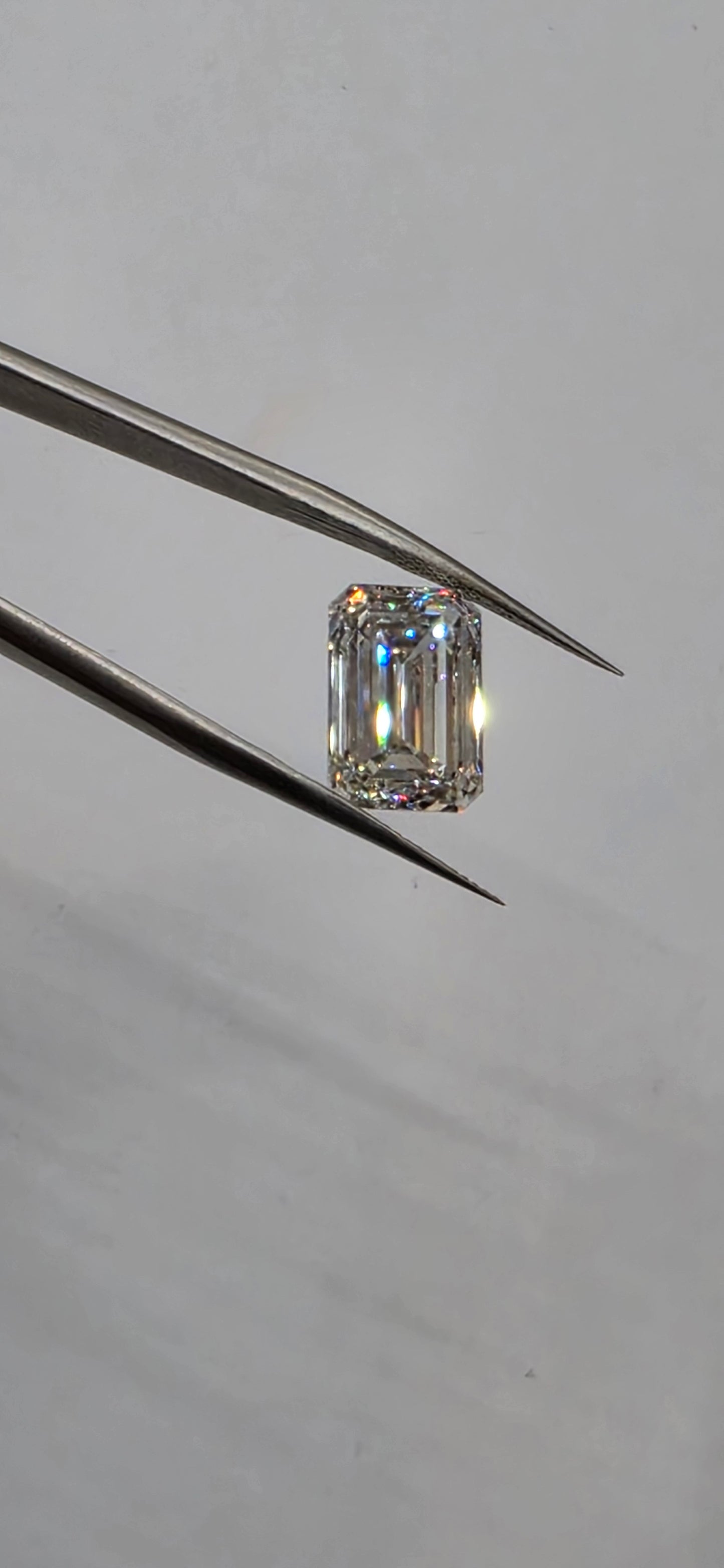 Diamond held by tweezers against a neutral background
