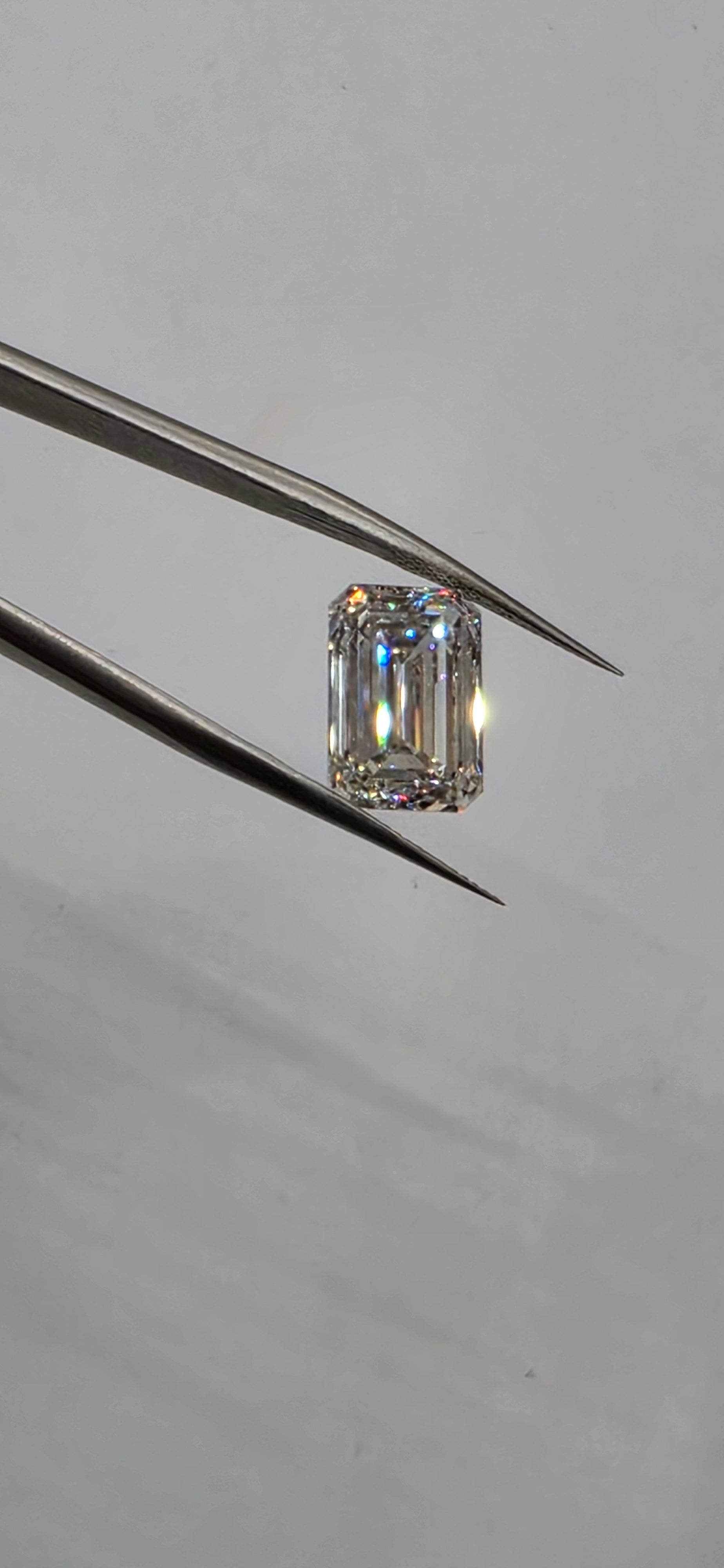 Diamond held by tweezers against a neutral background