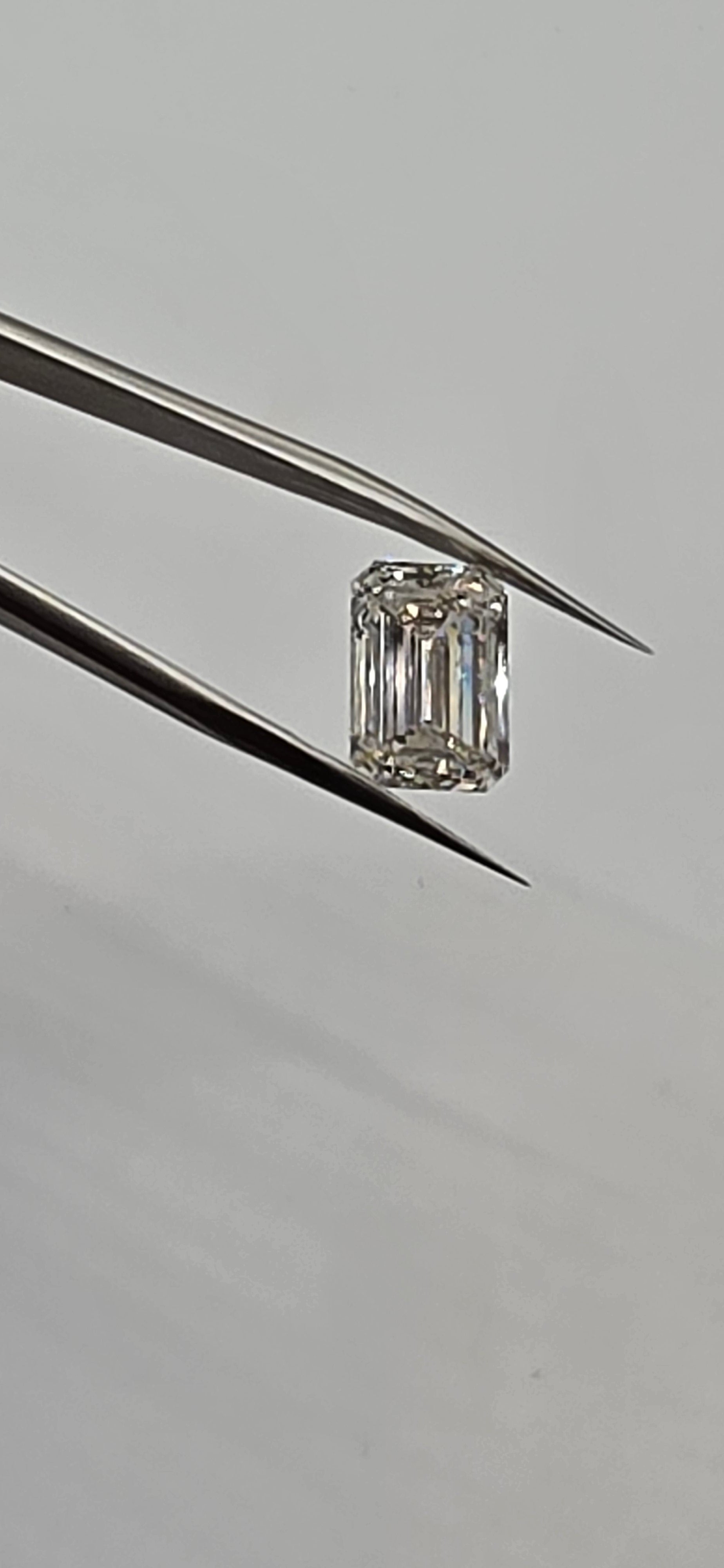 Diamond held between tweezers on a gray background