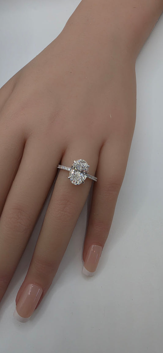 White gold ring with a diamond on a person's finger against a white background