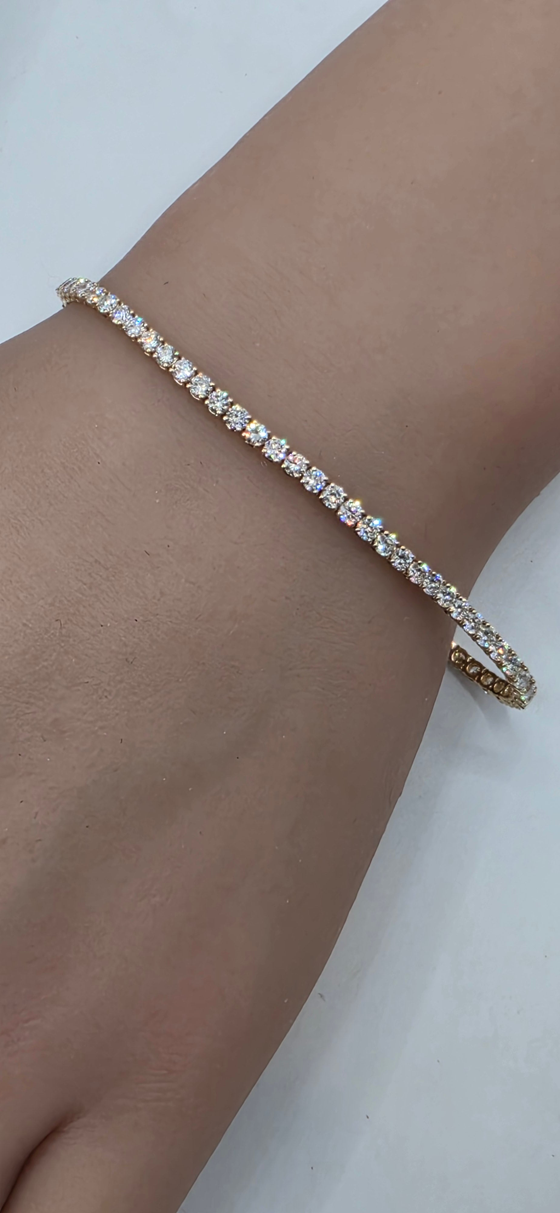 Gold bracelet with clear stones on a wrist against a white background