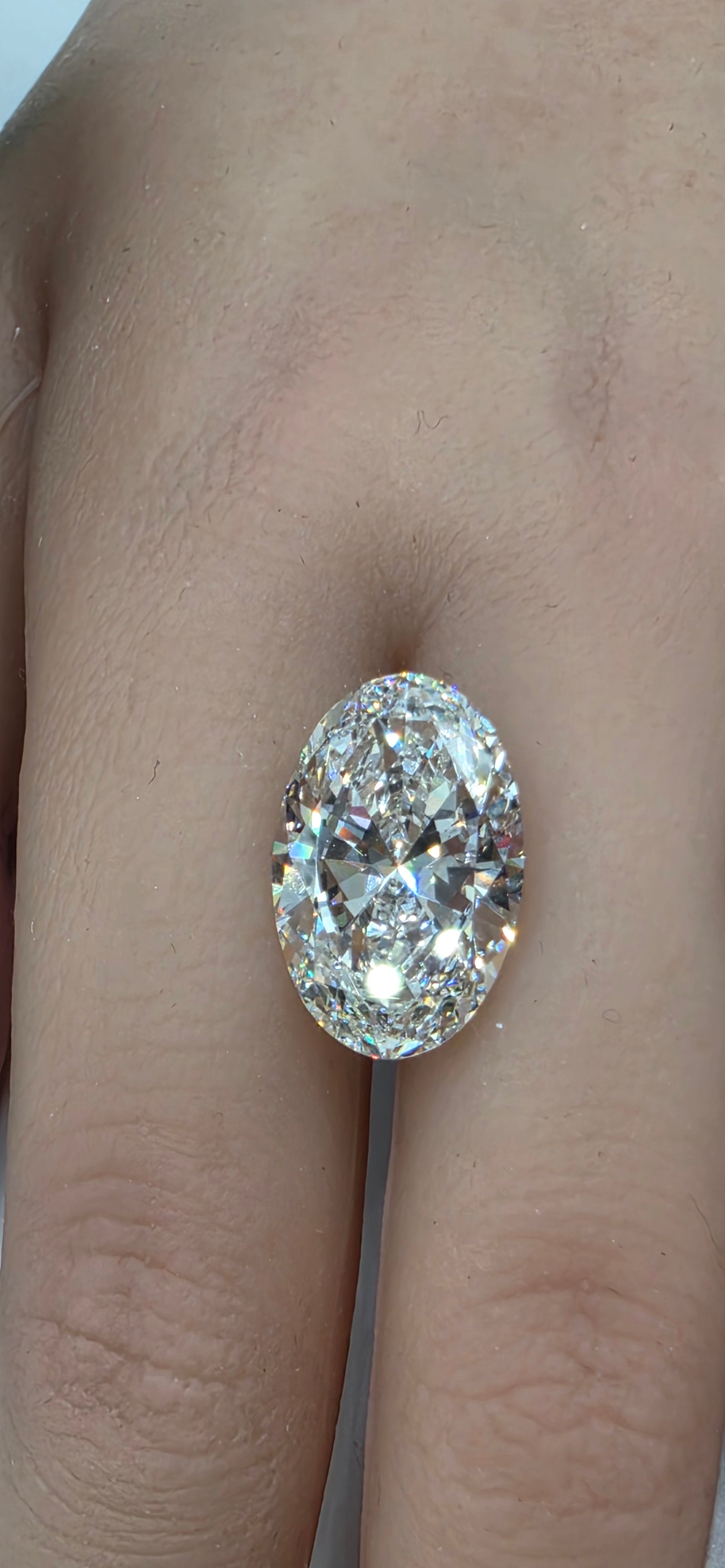 Diamond held between two fingers against a skin background