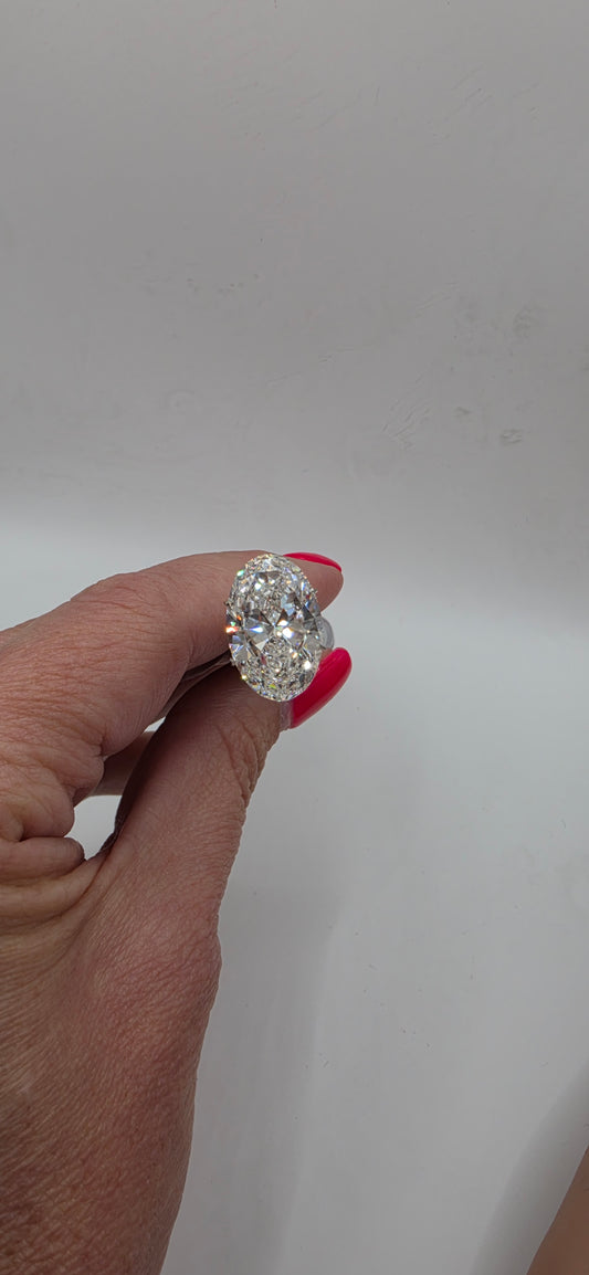Hand holding a diamond ring against a plain background
