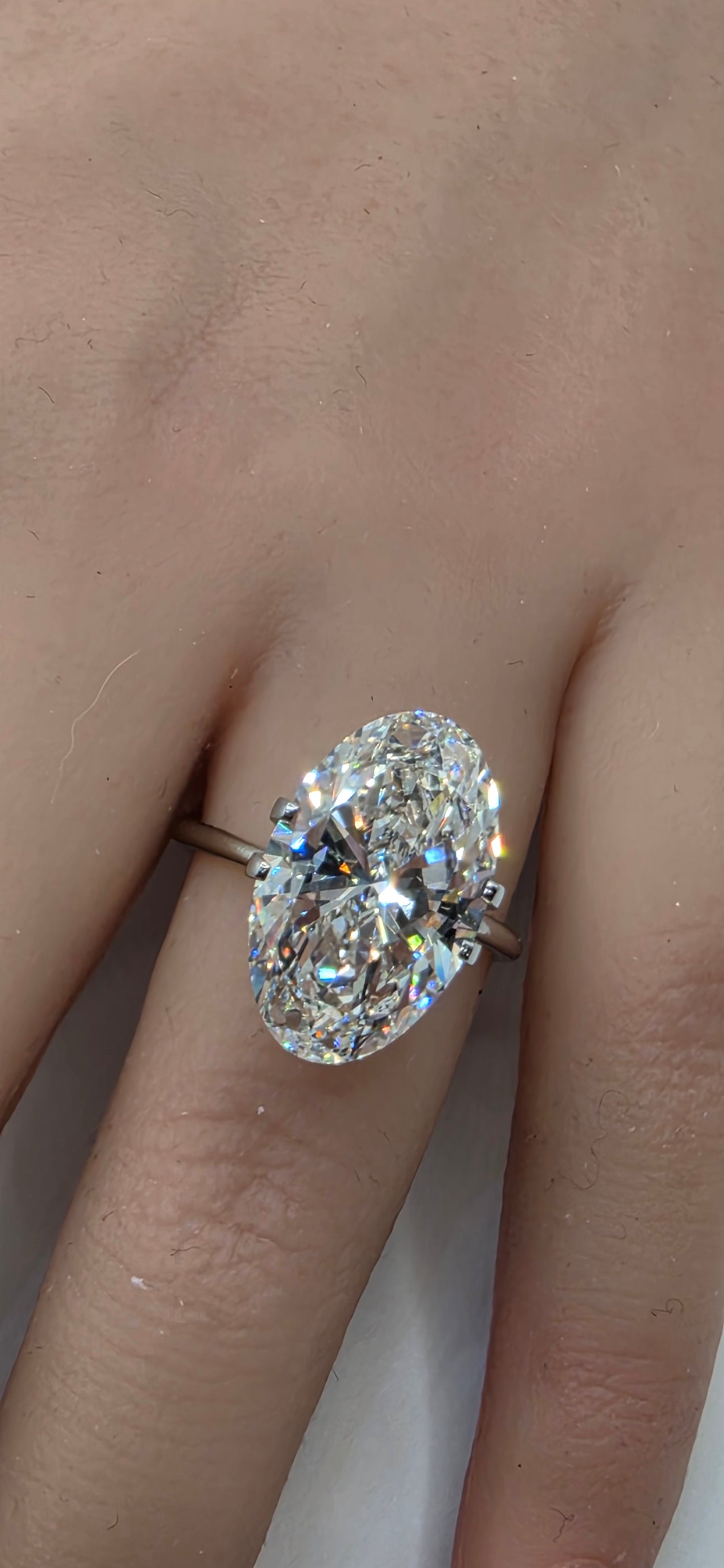 Diamond ring on a finger with a plain background