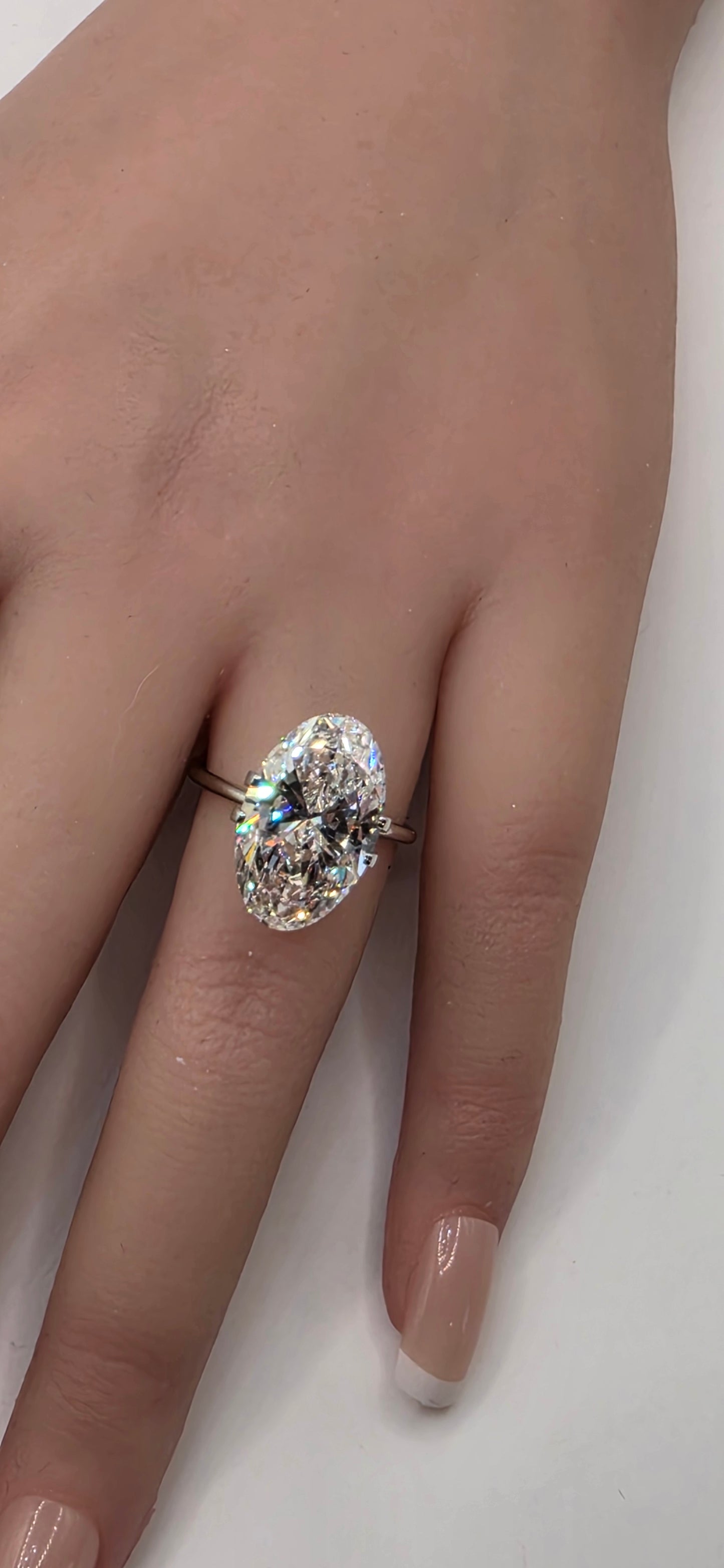 Diamond ring on a finger against a neutral background
