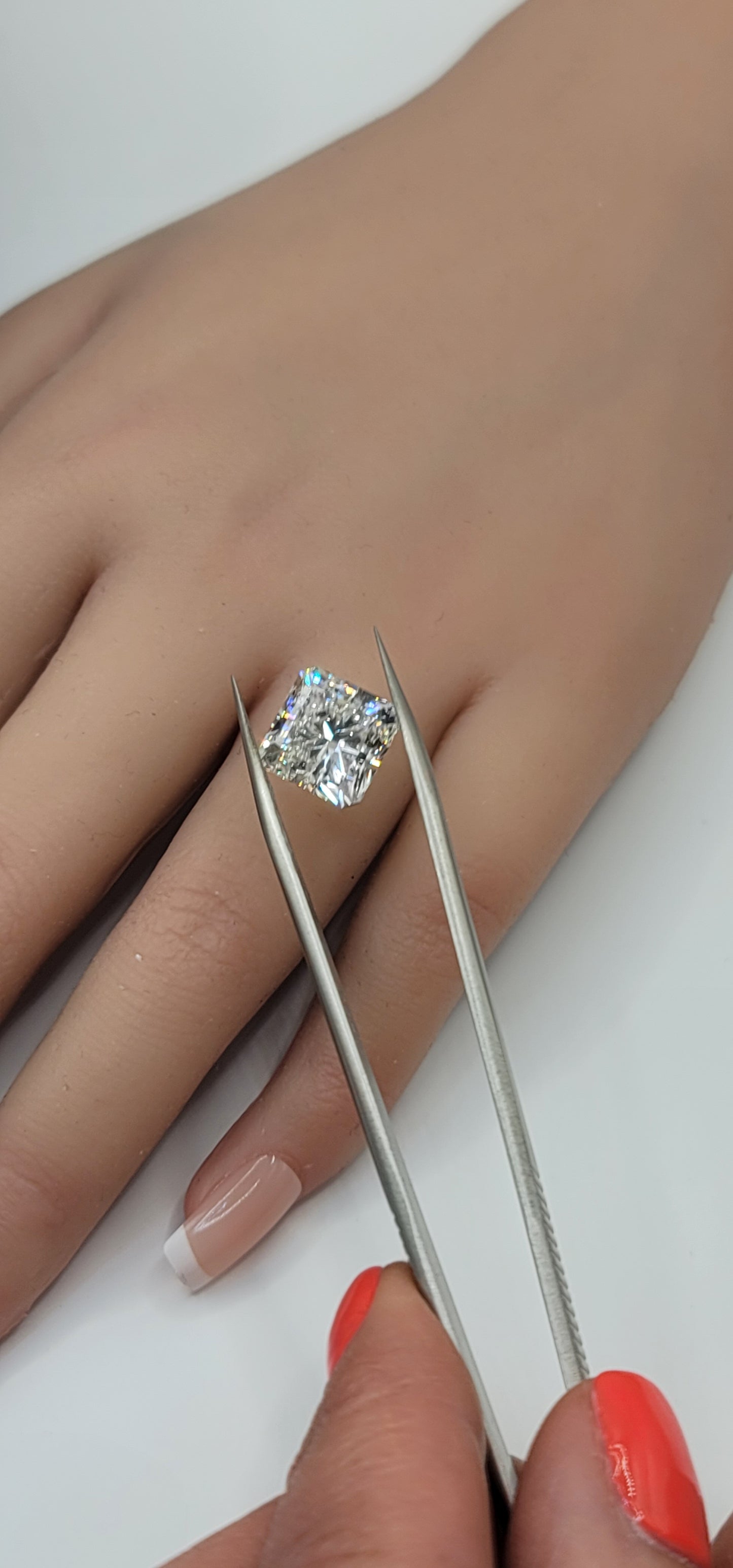 Square diamond in tweezers in front of a hand