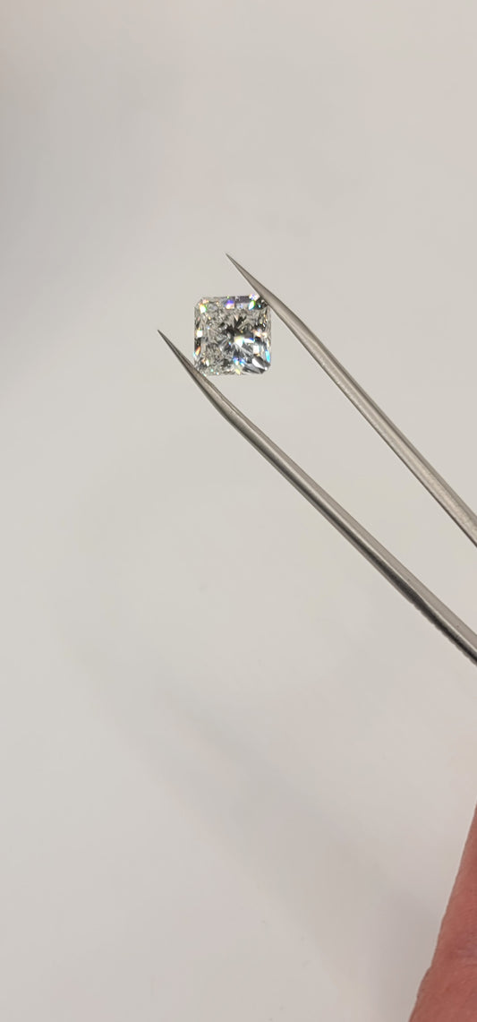 Square diamond held by tweezers against a white background