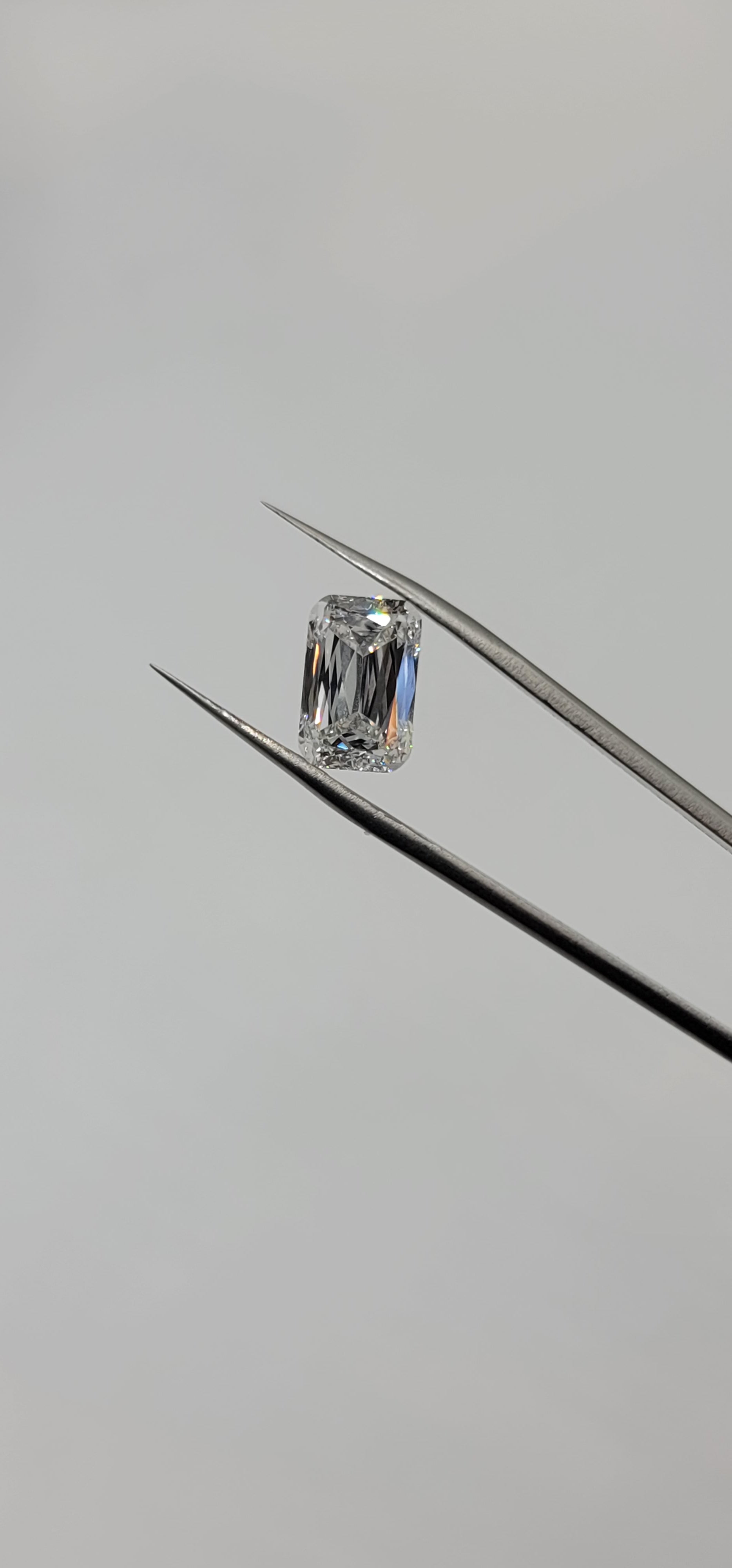 Diamond held by tweezers on a gray background
