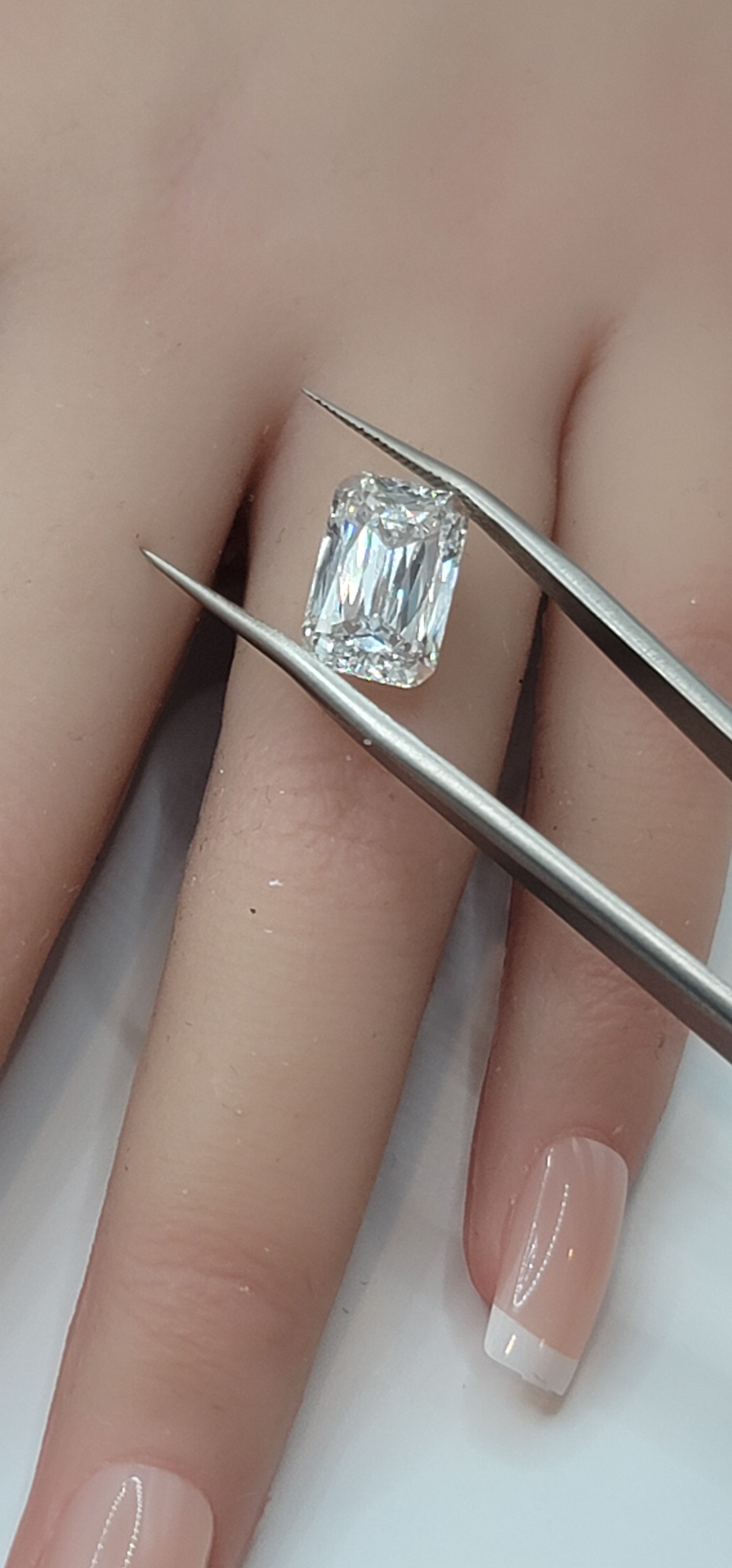 Diamond held between tweezers against a blurred background