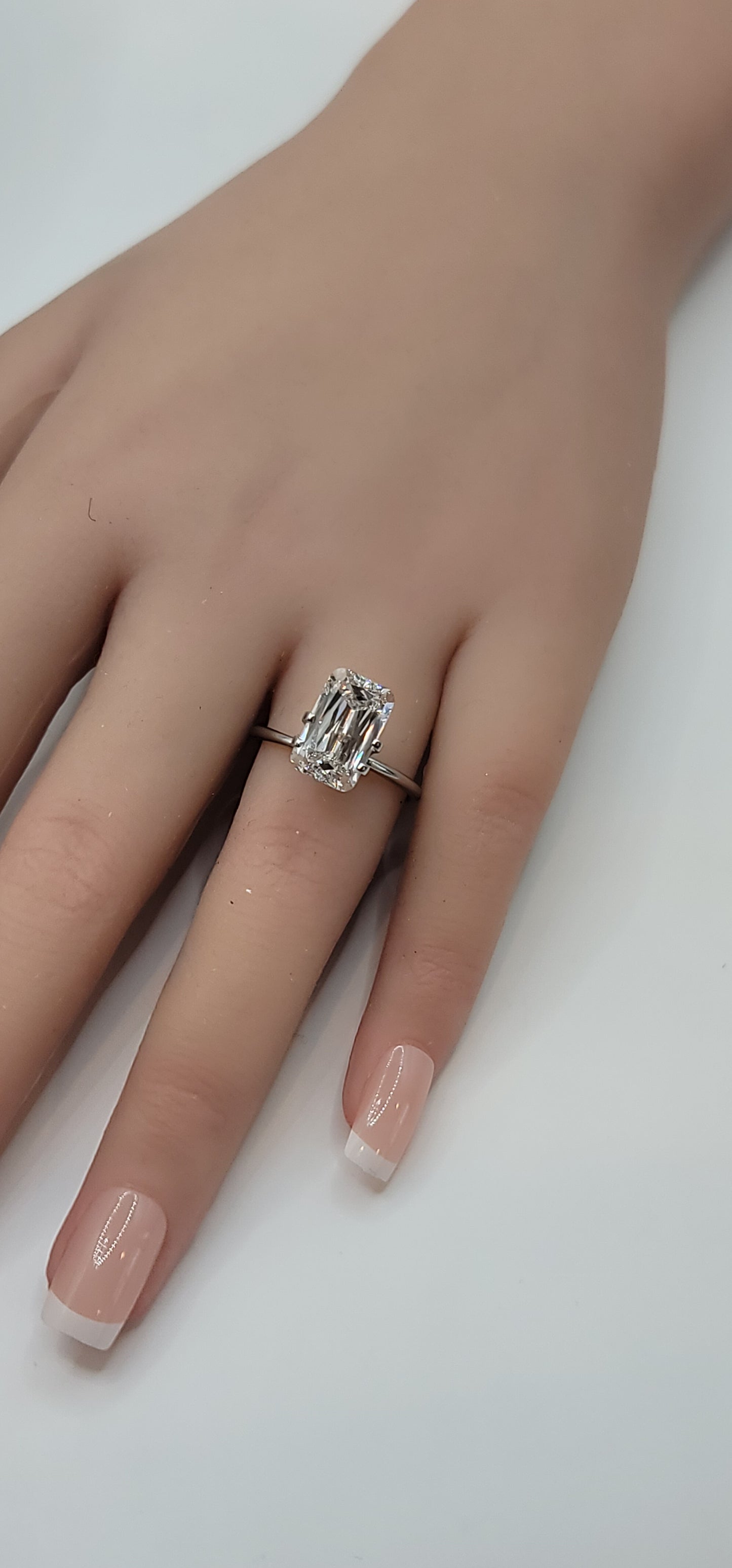 Hand wearing a silver ring with a diamond on a white background