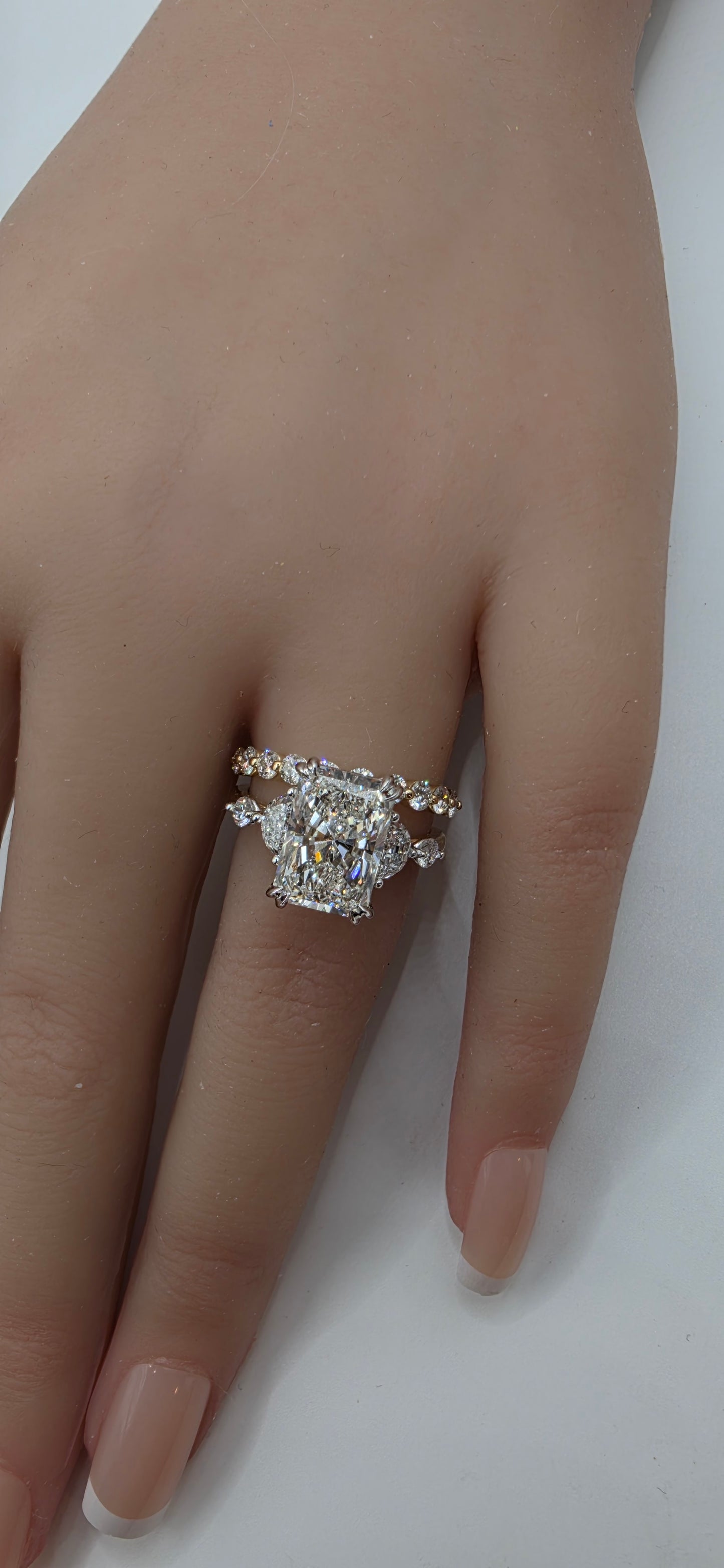 Hand wearing a diamond ring on a plain background