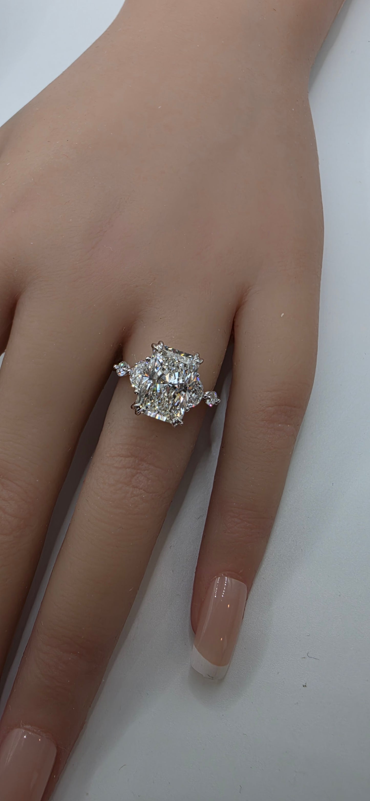 Gold ring with diamonds on a finger against a white background