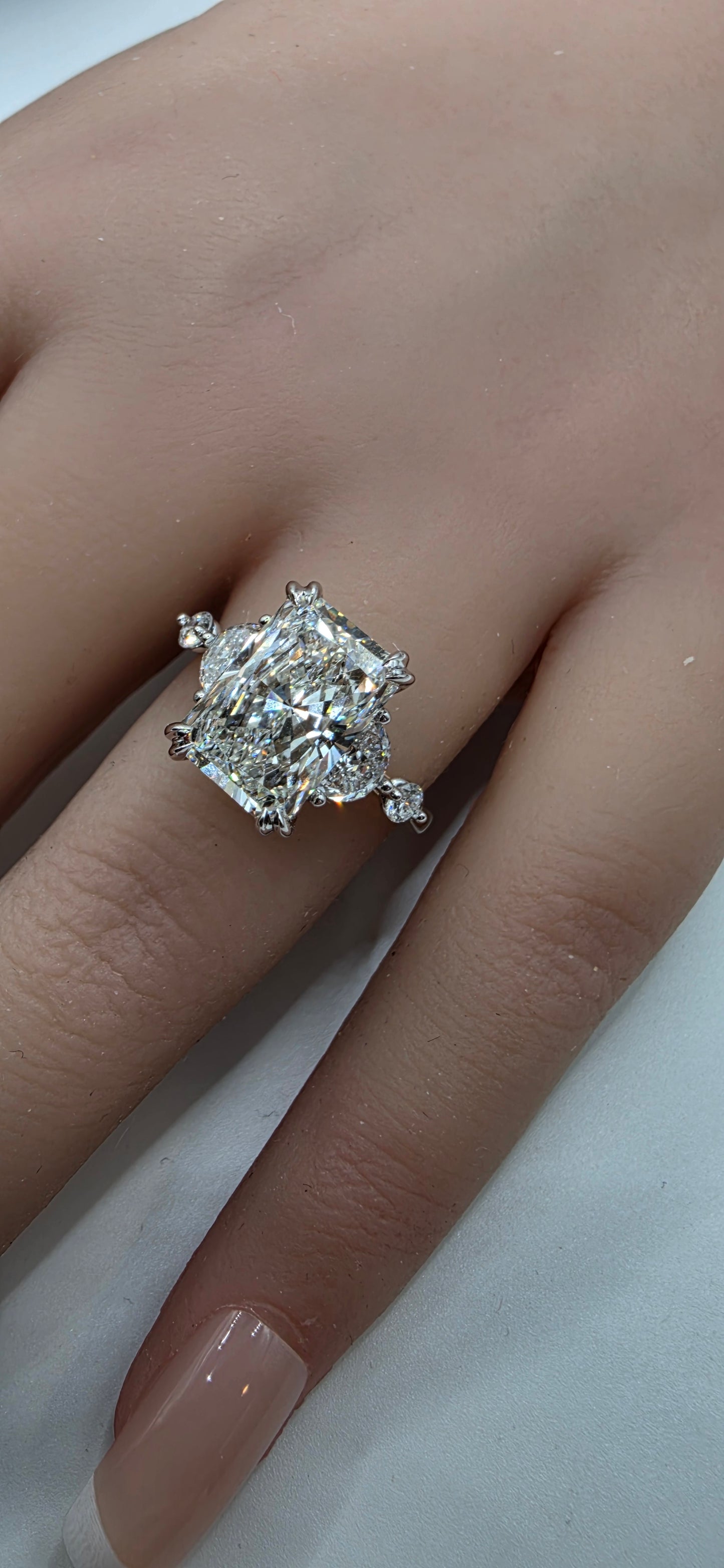Diamond ring on a finger against a neutral background