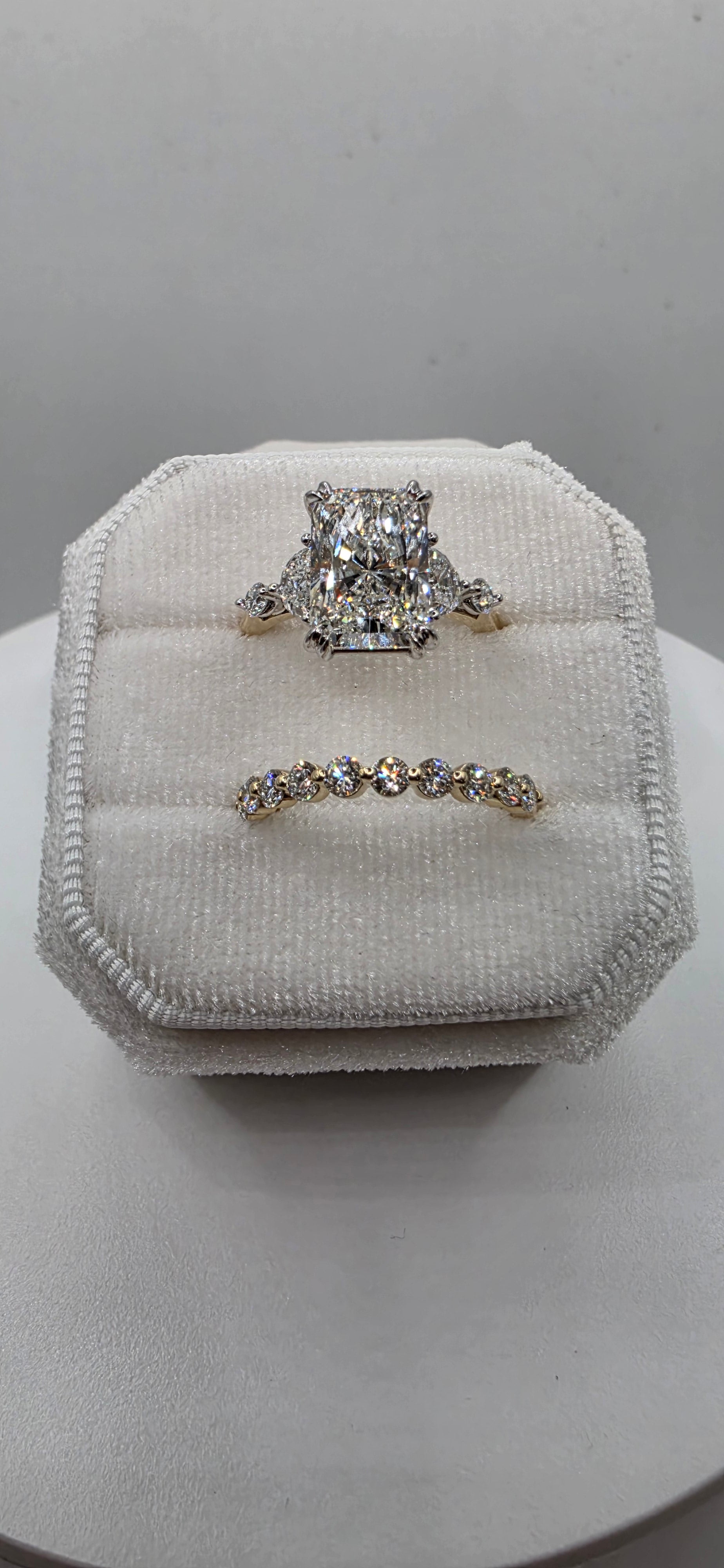 Pair of silver earrings on a white cushioned stand against a neutral background
