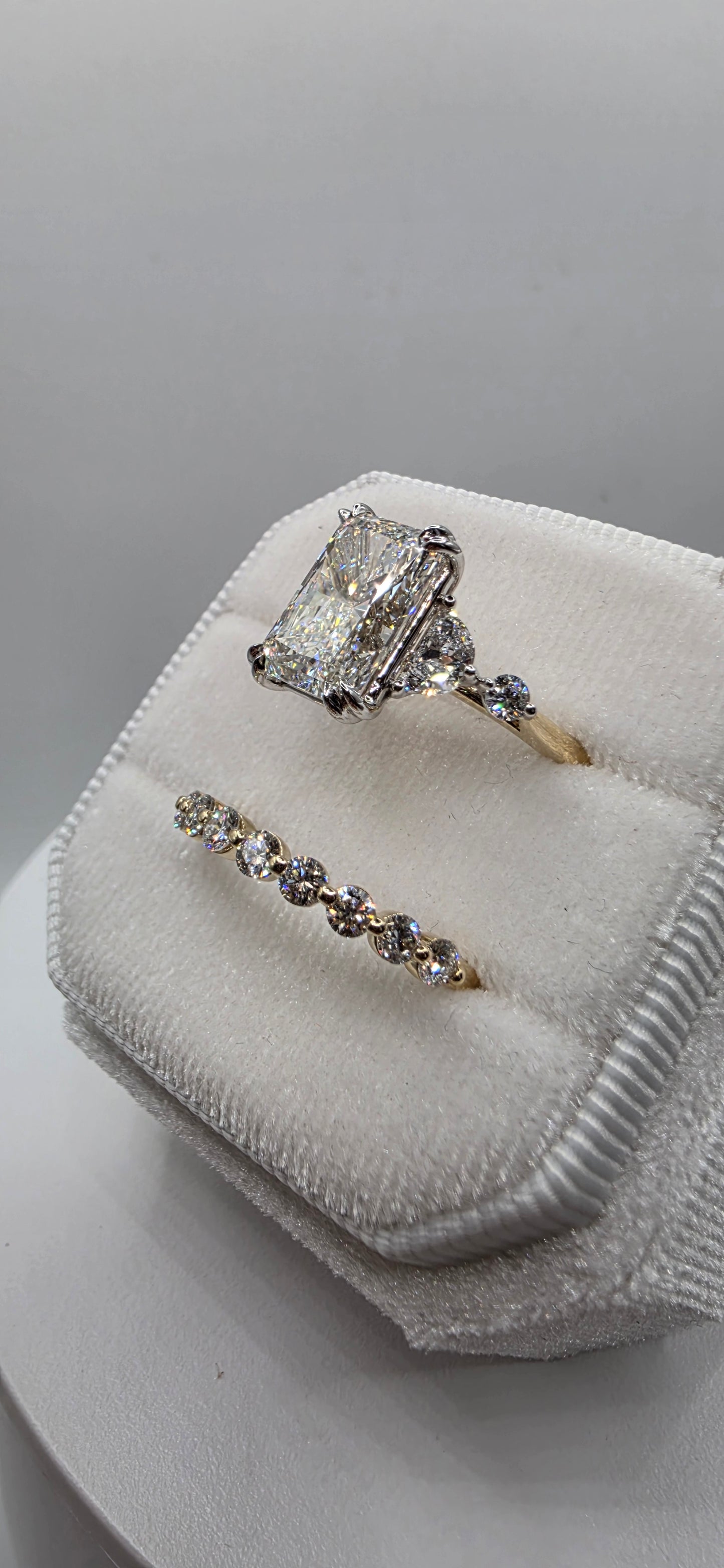 Pair of diamond earrings on a white cushioned stand with a gray background