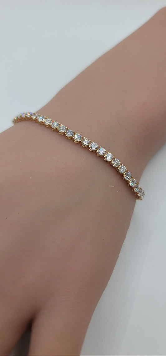 Yellow gold bracelet with clear stones on a wrist against a white background