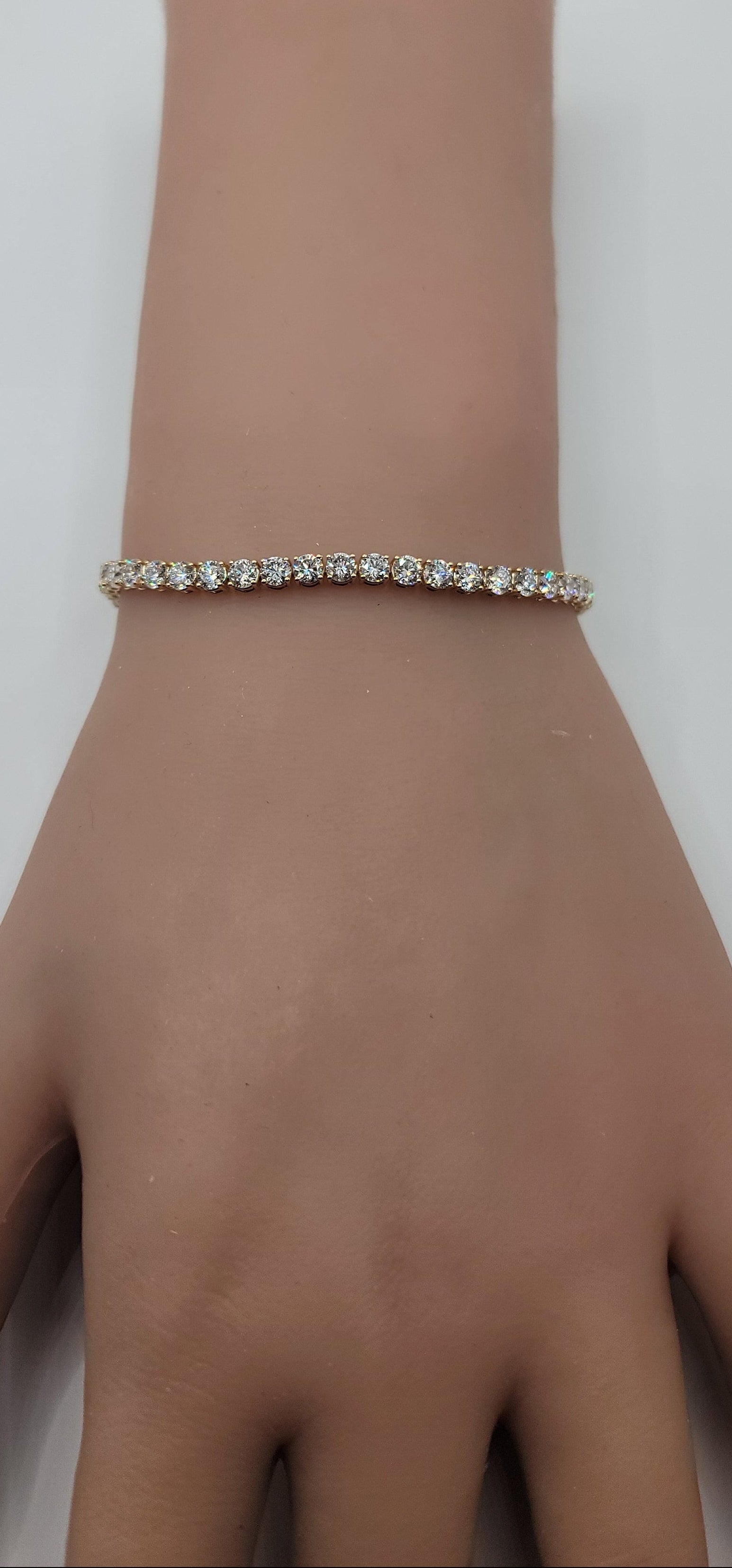 Yellow gold bracelet on a wrist against a white background