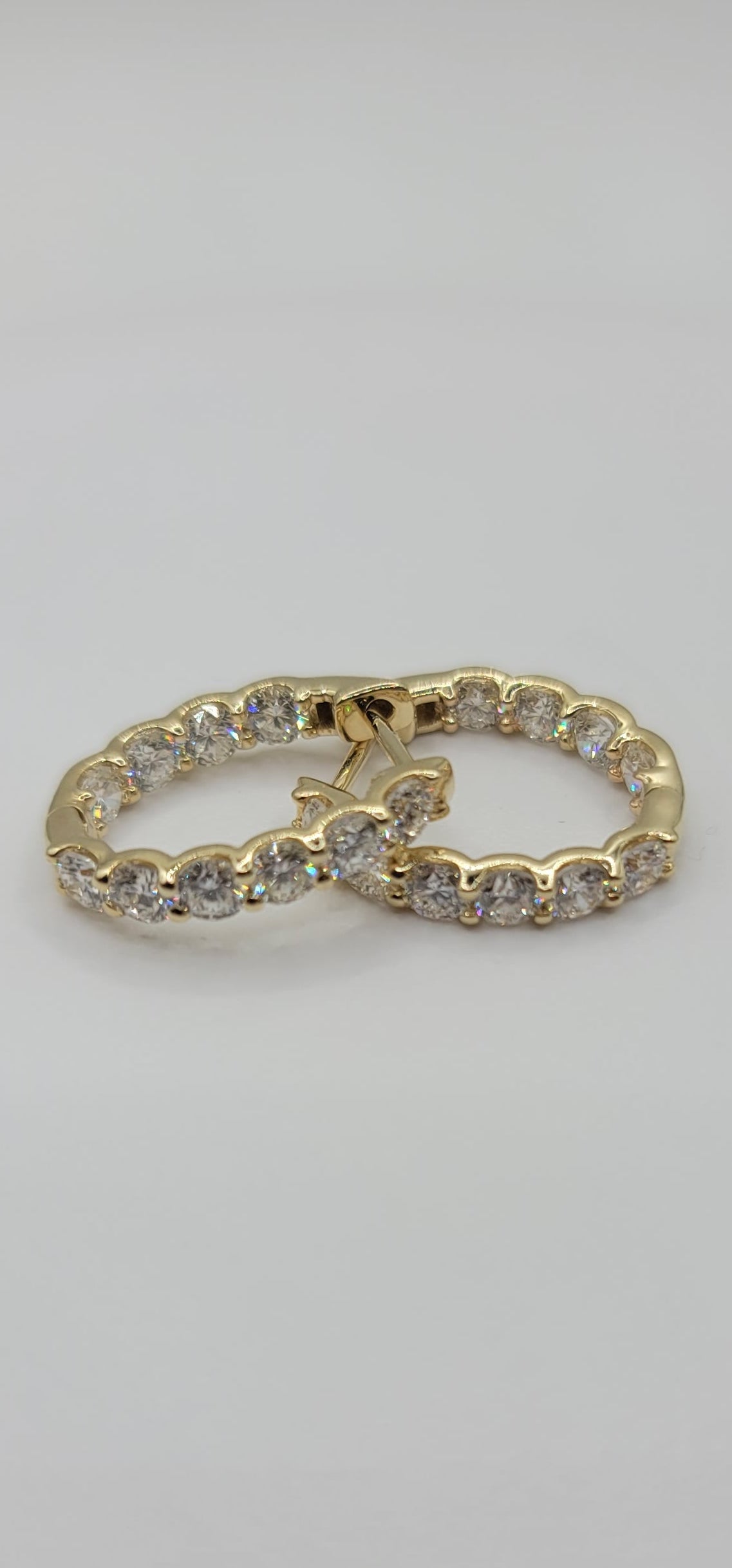 Gold earrings with embedded stones inside and out on a light gray background