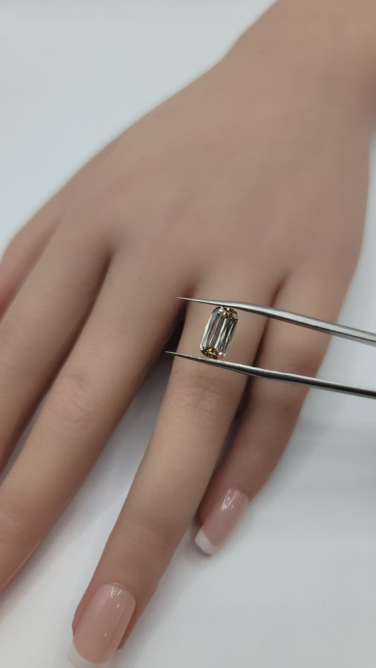 A lab grown crisscut diamond held with tweezers agains a womans hand.  