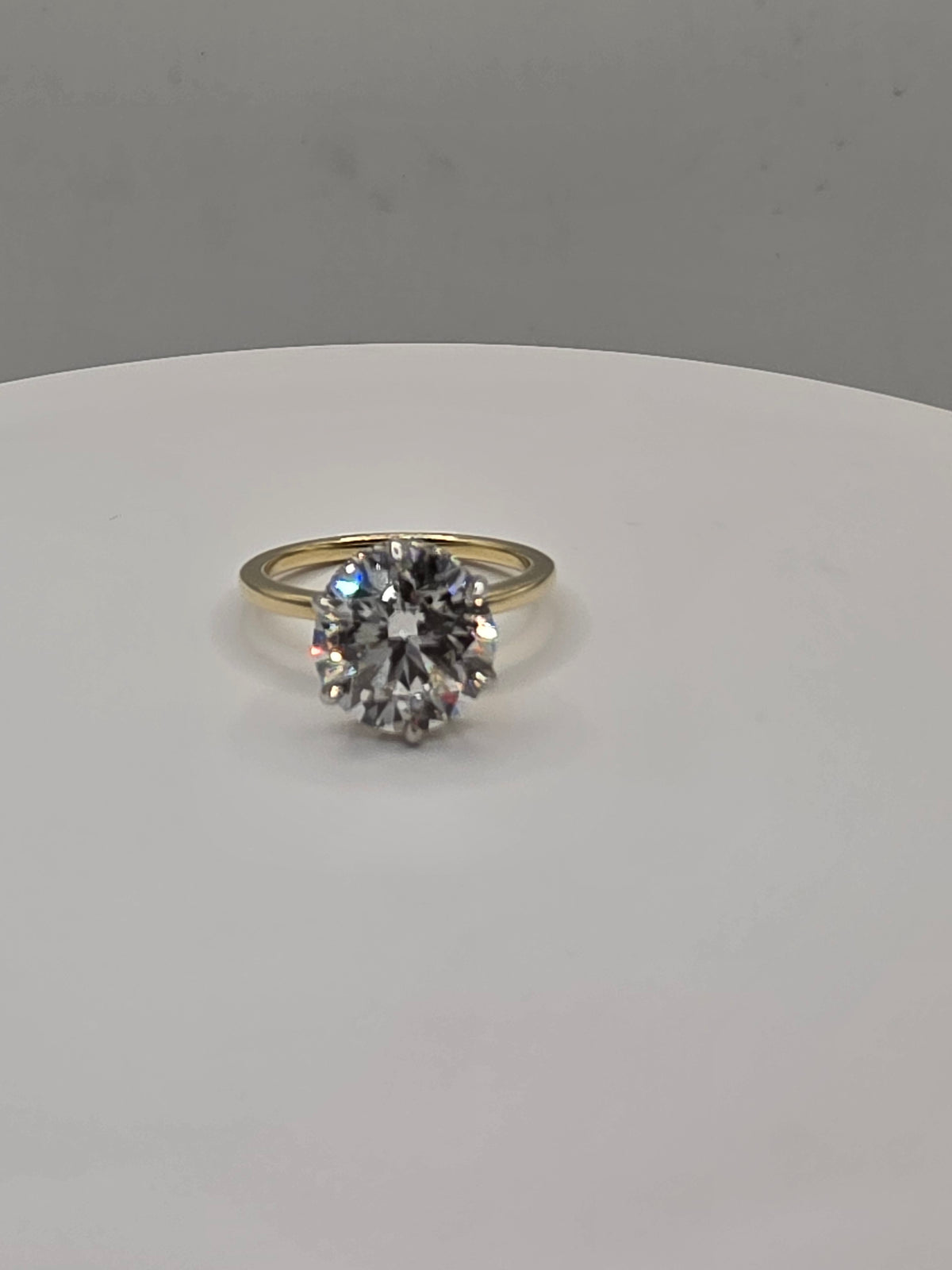 Round diamond ring with yellow gold on a white background